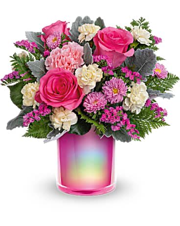Pink and cream flower arrangement in a rainbow-tinted glass vase