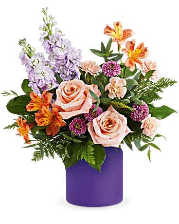 Mixed bouquet of roses, lilies, and purple flowers in a purple vase