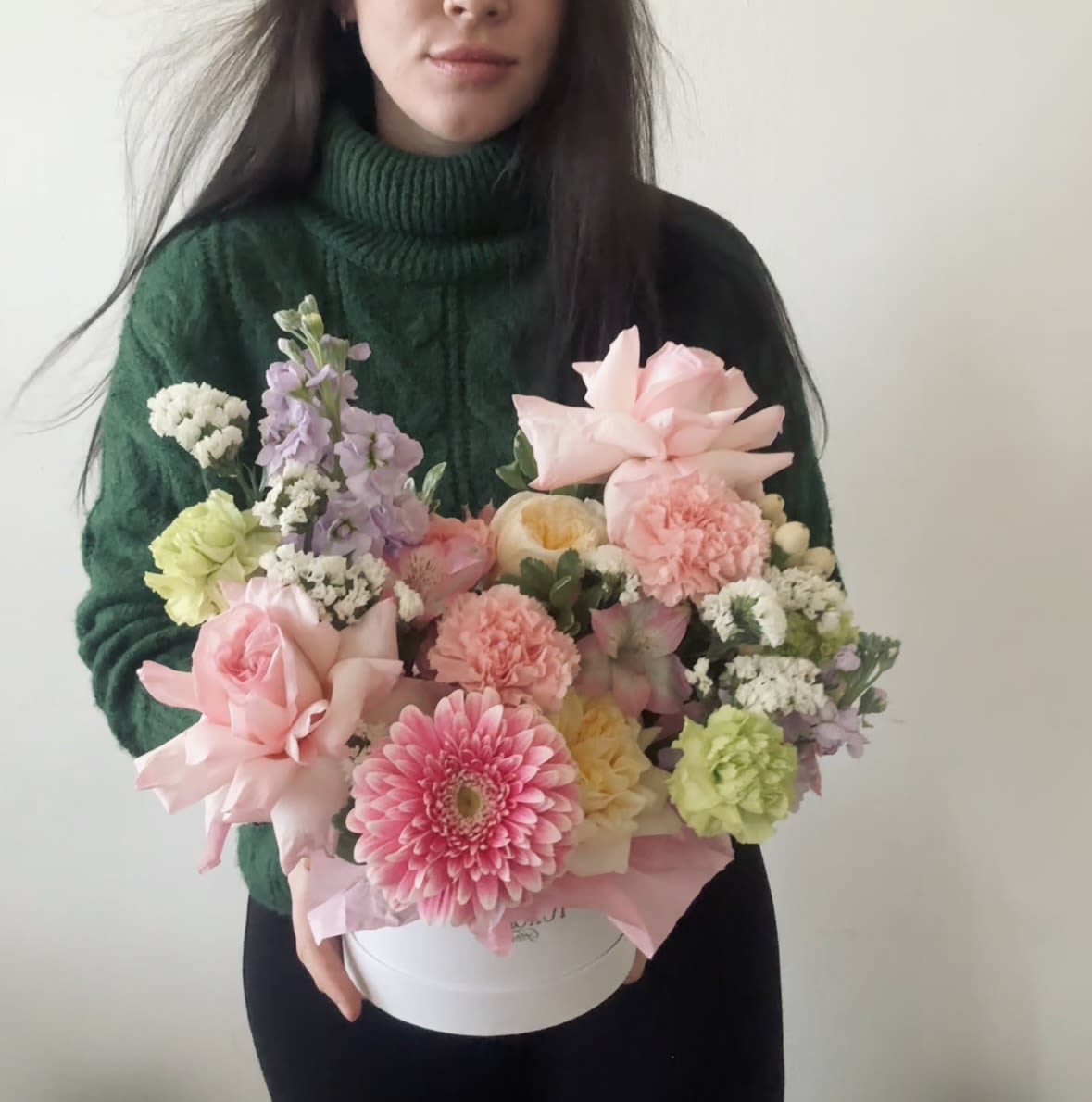 Woman holding a pastel mixed flower arrangement in a white box