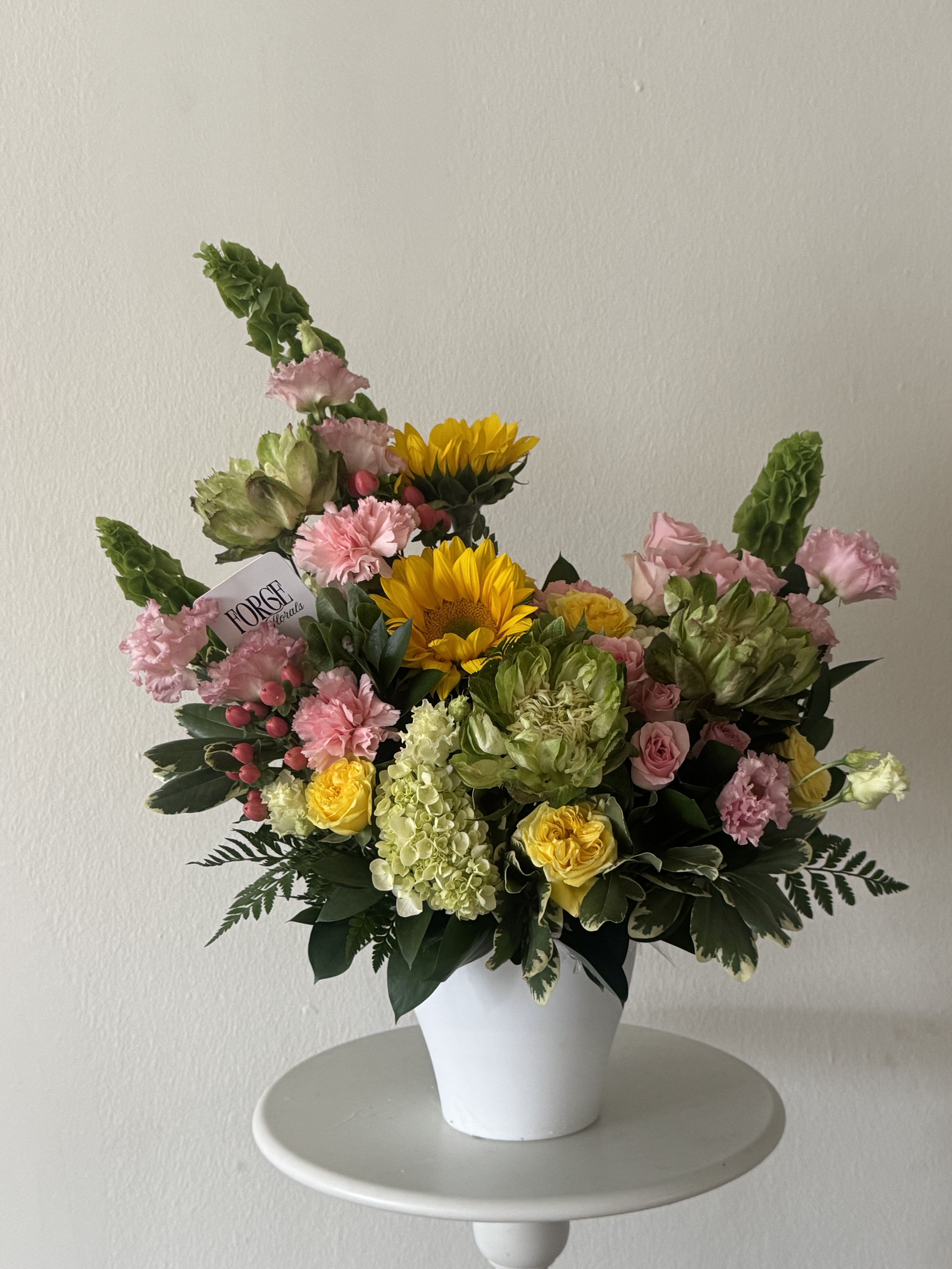 Garden Melody -  cheerful garden-style arrangement featuring premium seasonal blooms in soft pink, fresh green, and sunny yellow tones. Designed in a keepsake ceramic container for a naturally elegant look.  Availability Note: Green roses are seasonal. When unavailable, they will be replaced with a similar premium flower of equal or greater value while maintaining the overall style and color palette.