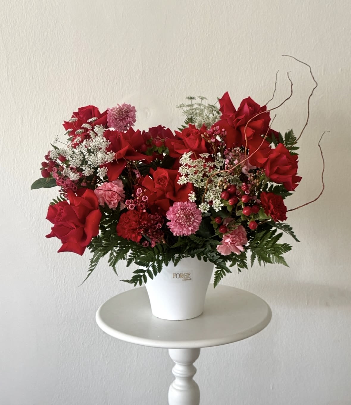 Ruby Romance- french red roses, dianthus, hypericum - A lush and elegant floral arrangement featuring rich red blooms accented with soft pink flowers, delicate white textures, and fresh seasonal greenery. Designed in a modern ceramic container, this timeless arrangement is perfect for birthdays, anniversaries, romantic occasions, or simply making someone’s day a little brighter.  Please note: Flower varieties may vary based on seasonal availability while maintaining the overall style, color palette, and value of the arrangement.