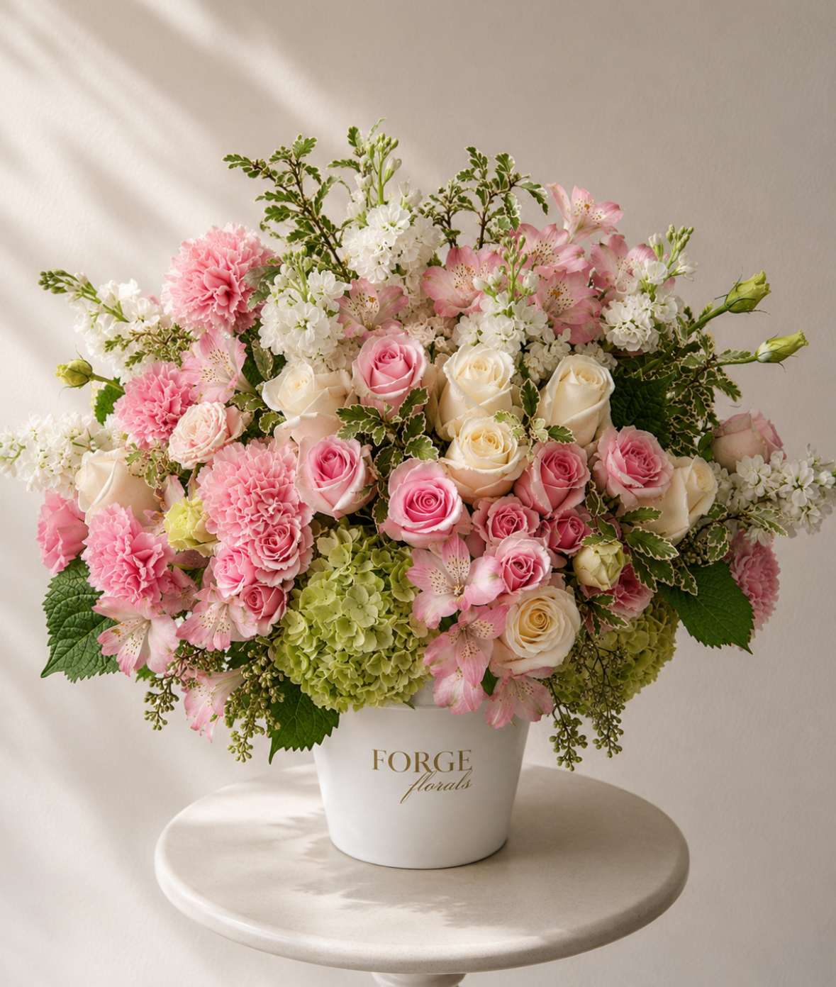 Pink and white floral arrangement in a white container
