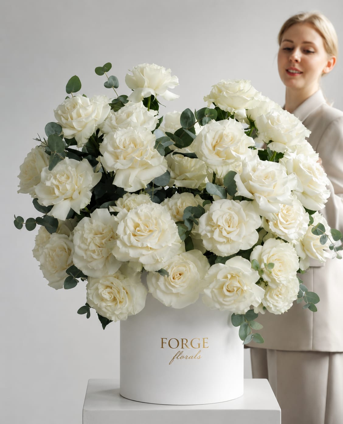 Large white rose arrangement in a white hat box with eucalyptus