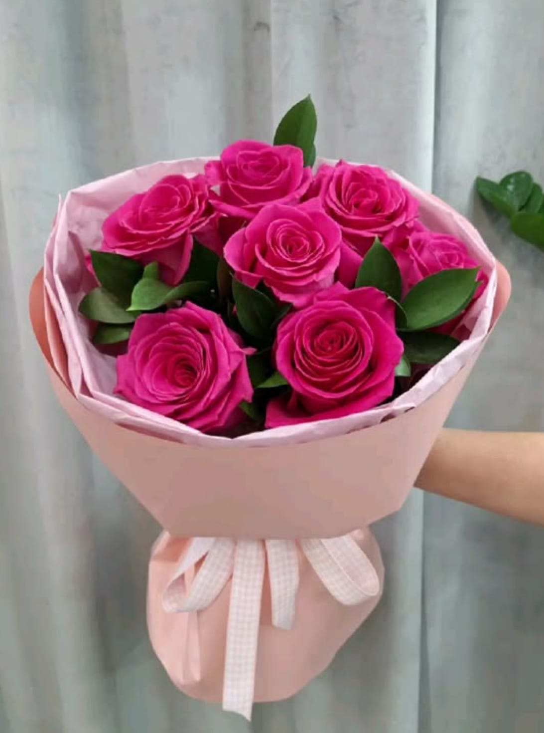 Bouquet of bright pink roses wrapped in pale pink paper