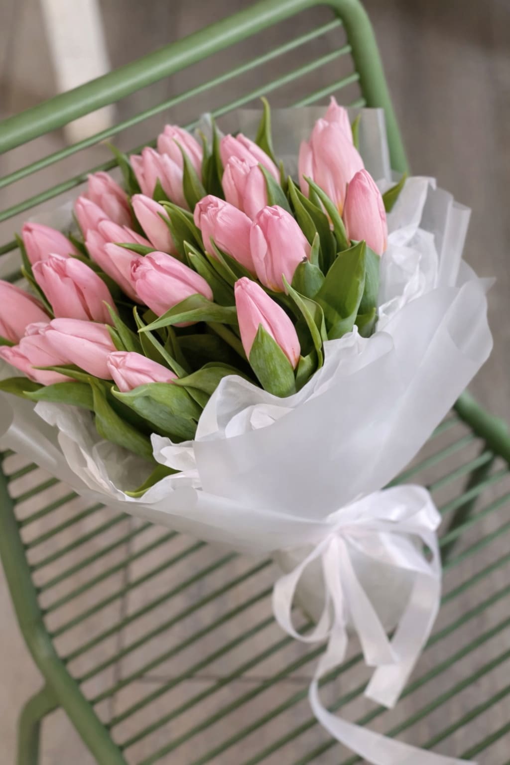 Bouquet of pink tulips wrapped in white paper with a ribbon