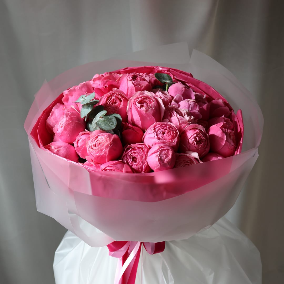 Pink rose bouquet wrapped in translucent paper with a ribbon