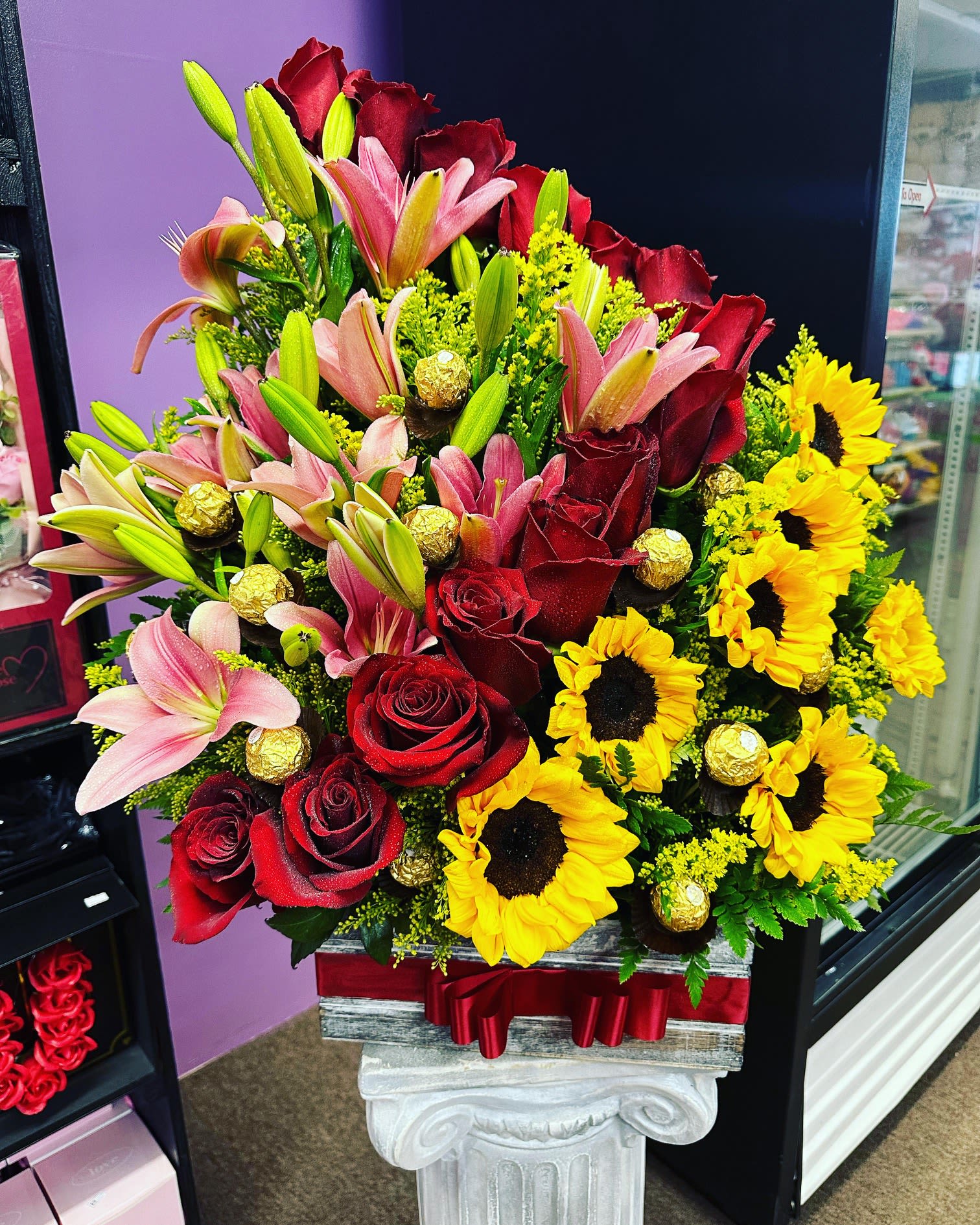 Mixed bouquet with red roses, pink lilies, and yellow sunflowers in a box