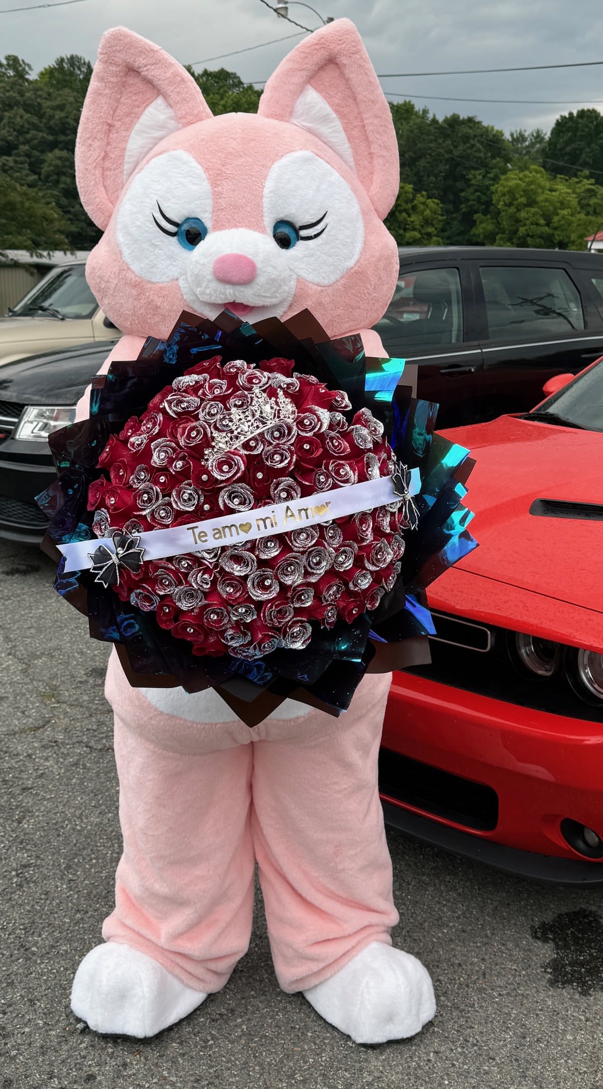 Pink bunny mascot holding a red rose bouquet with a ribbon