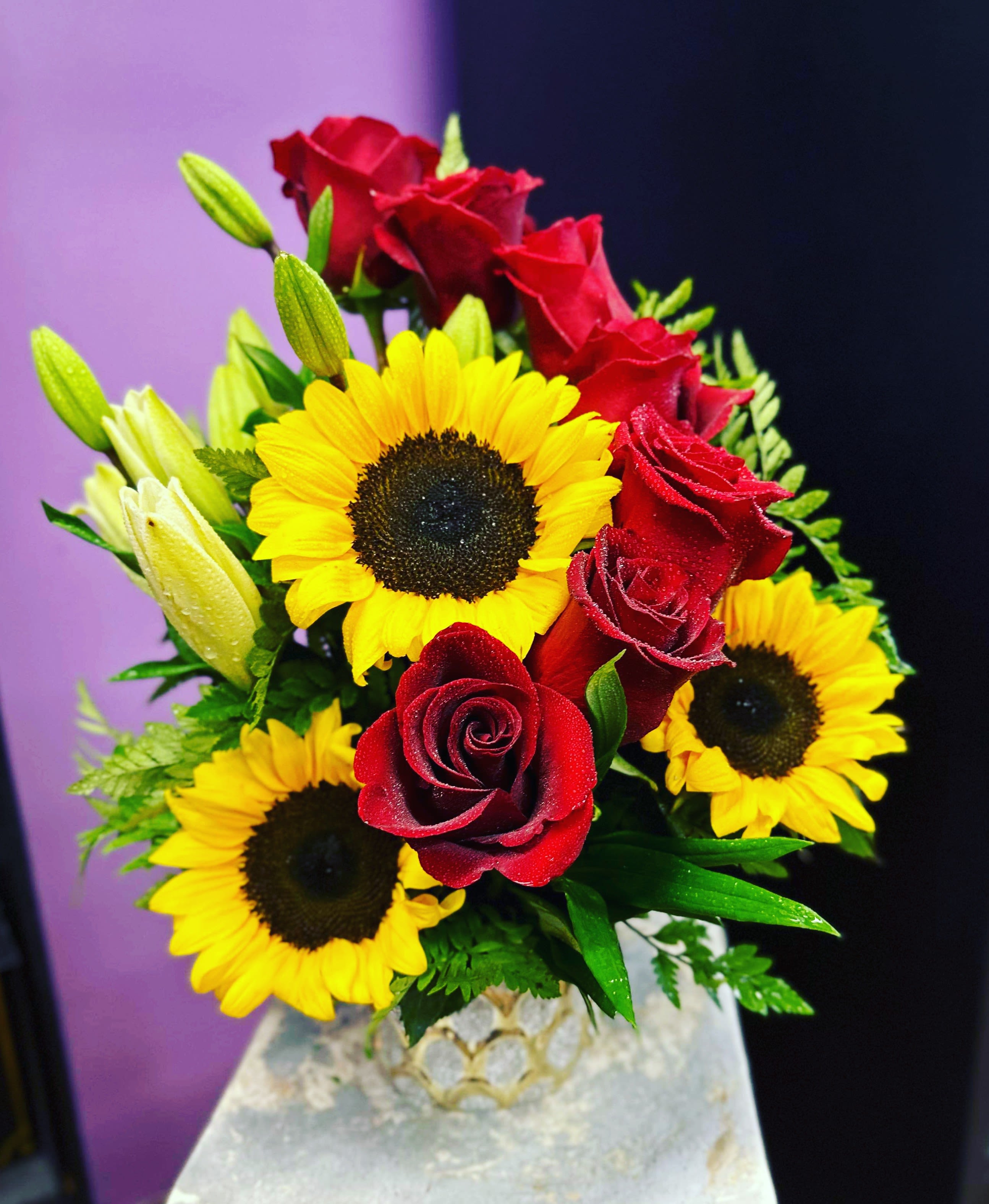 Bouquet of red roses and yellow sunflowers in a decorative vase