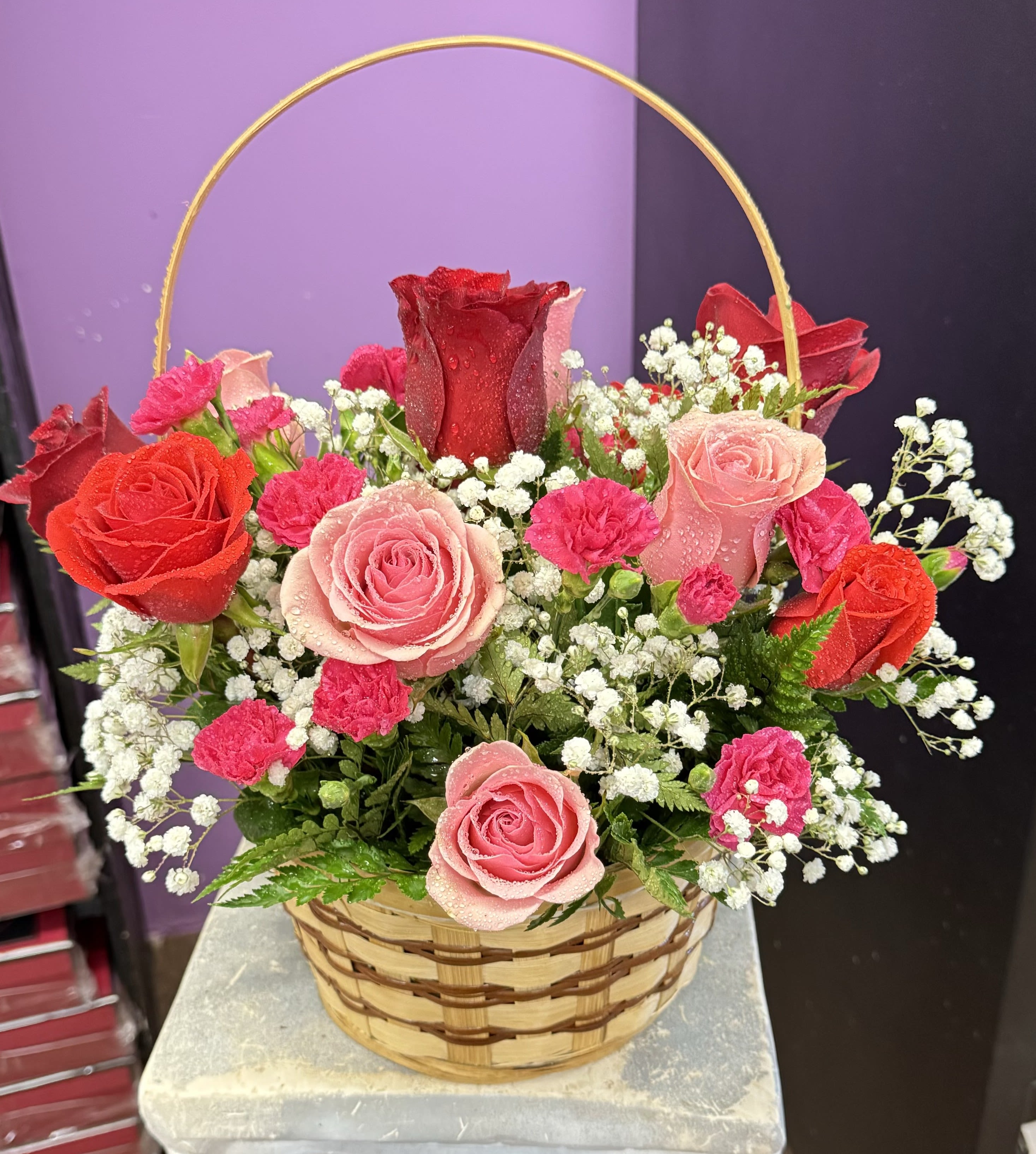 Basket arrangement of red and pink roses with white baby's breath