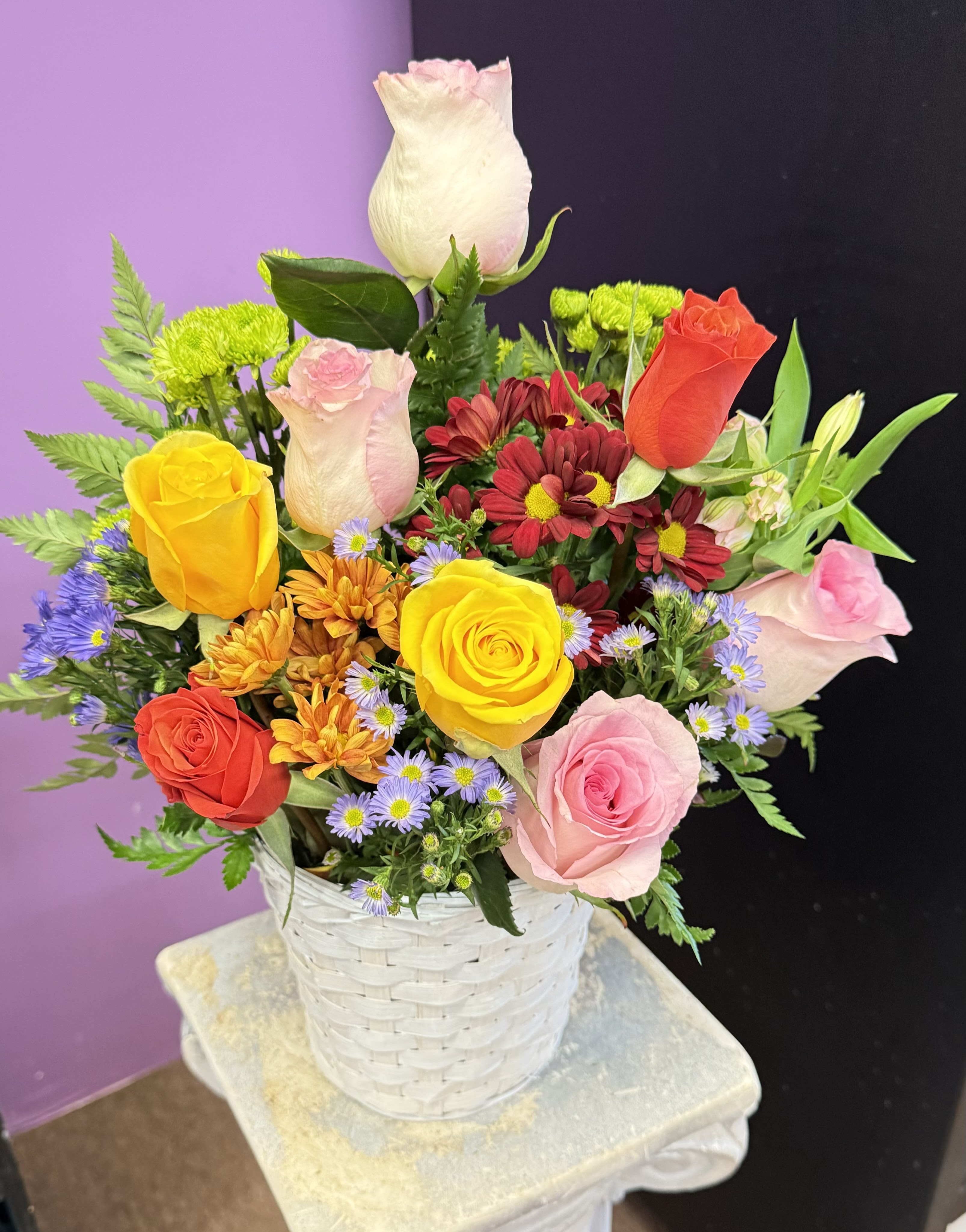 Mixed bouquet of roses and daisies in a white basket