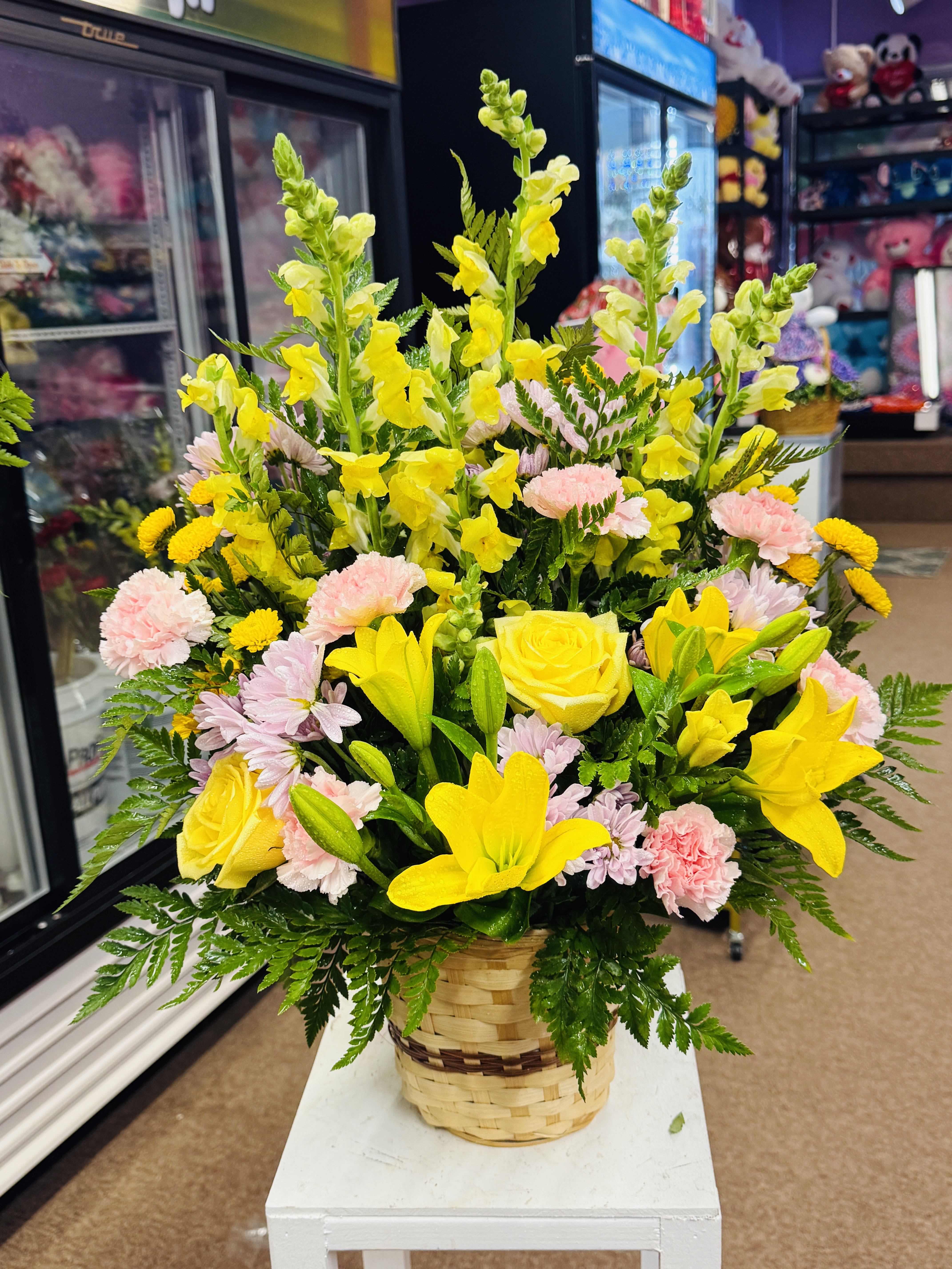 Basket arrangement of yellow lilies, roses, snapdragons, and pink carnations