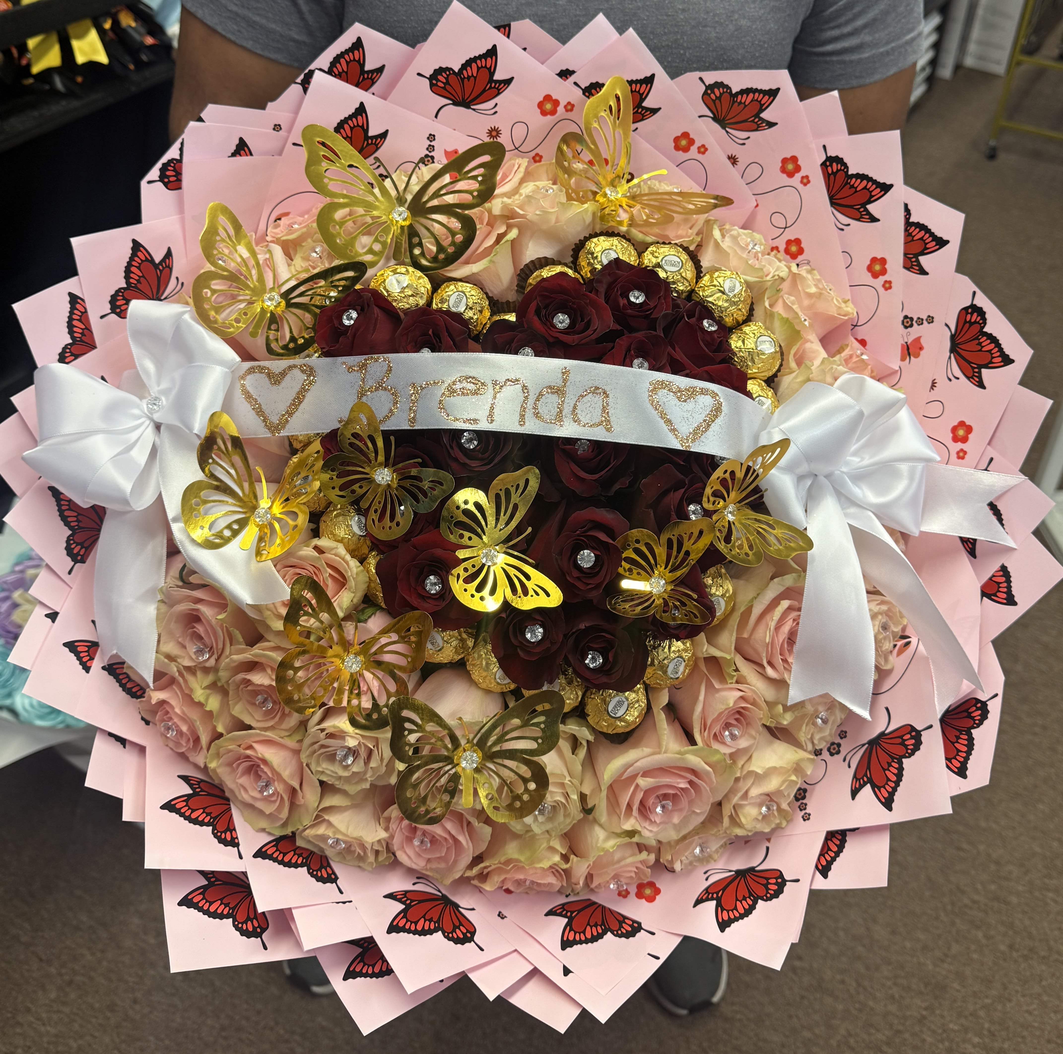 Bouquet of pink and burgundy roses with butterfly decorations and a white ribbon