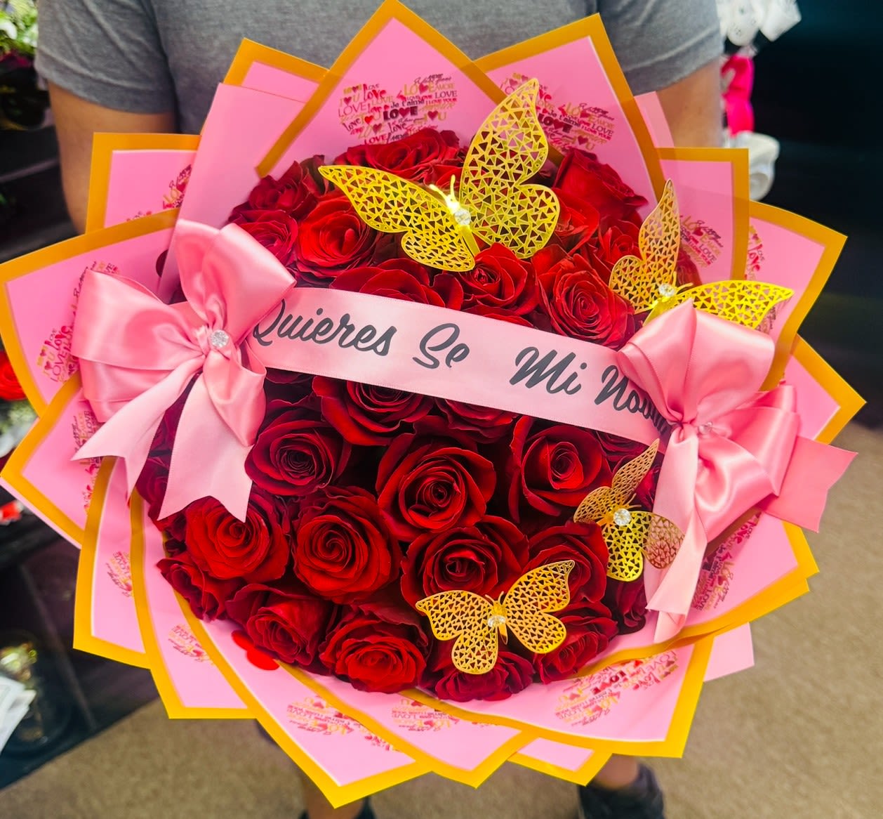 Bouquet of red roses with pink wrapping, bows, and butterfly decorations