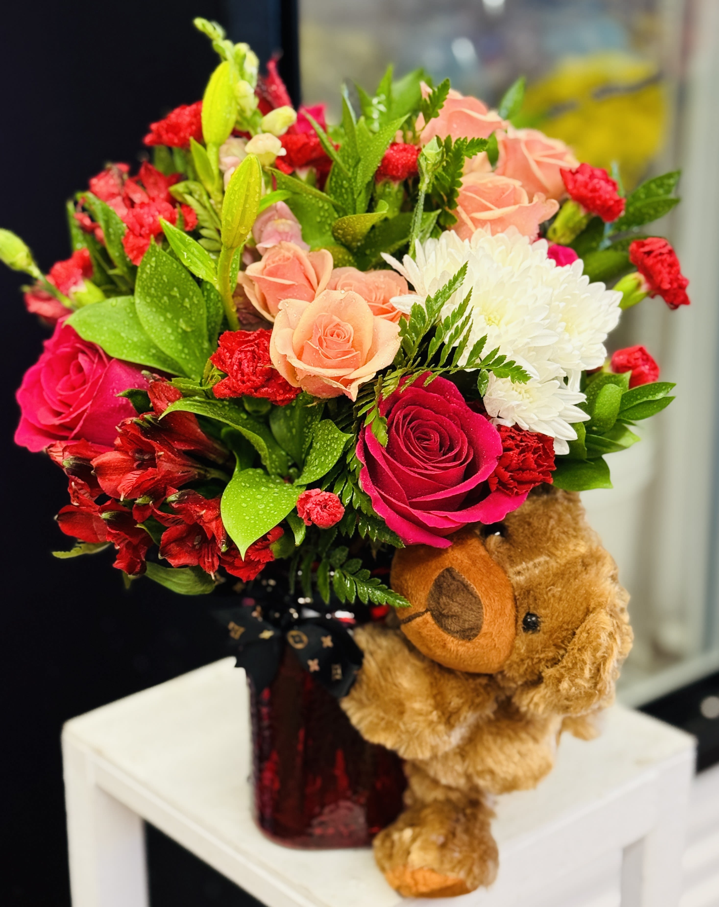 Bouquet of pink, peach, red, and white flowers with a teddy bear