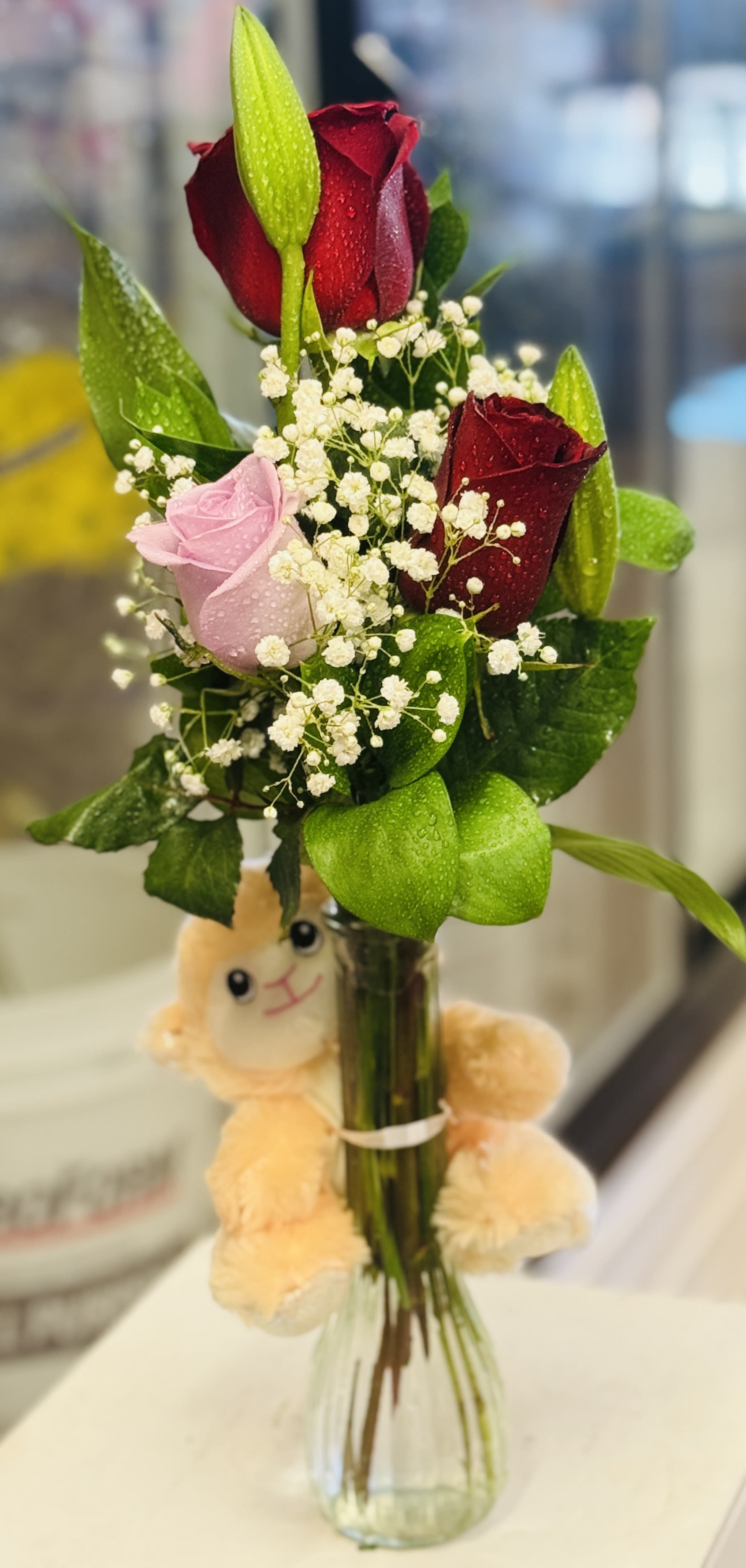 Bouquet of red and pink roses in a glass vase with a plush toy