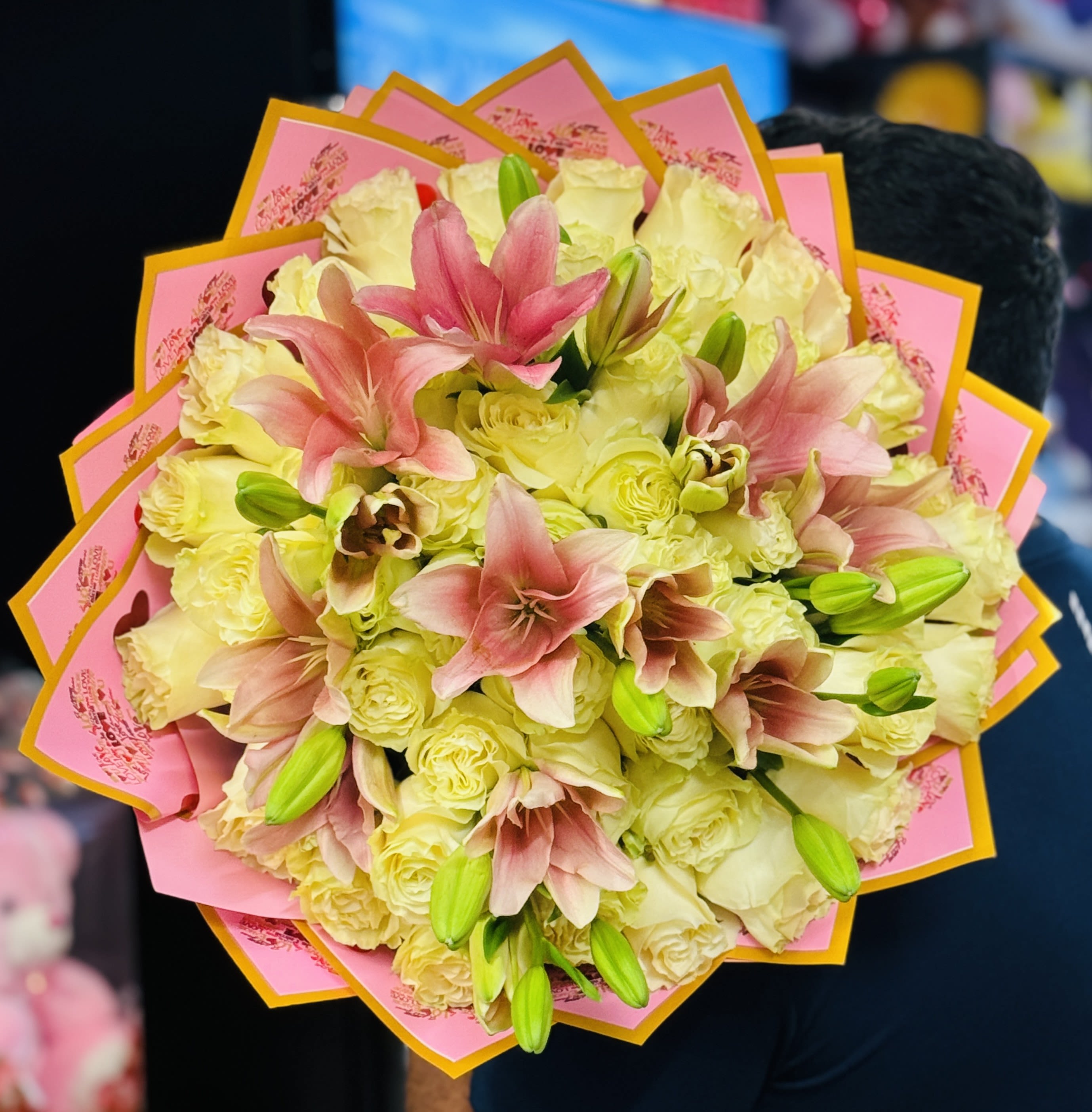 Bouquet of pale yellow roses and pink lilies wrapped in pink paper