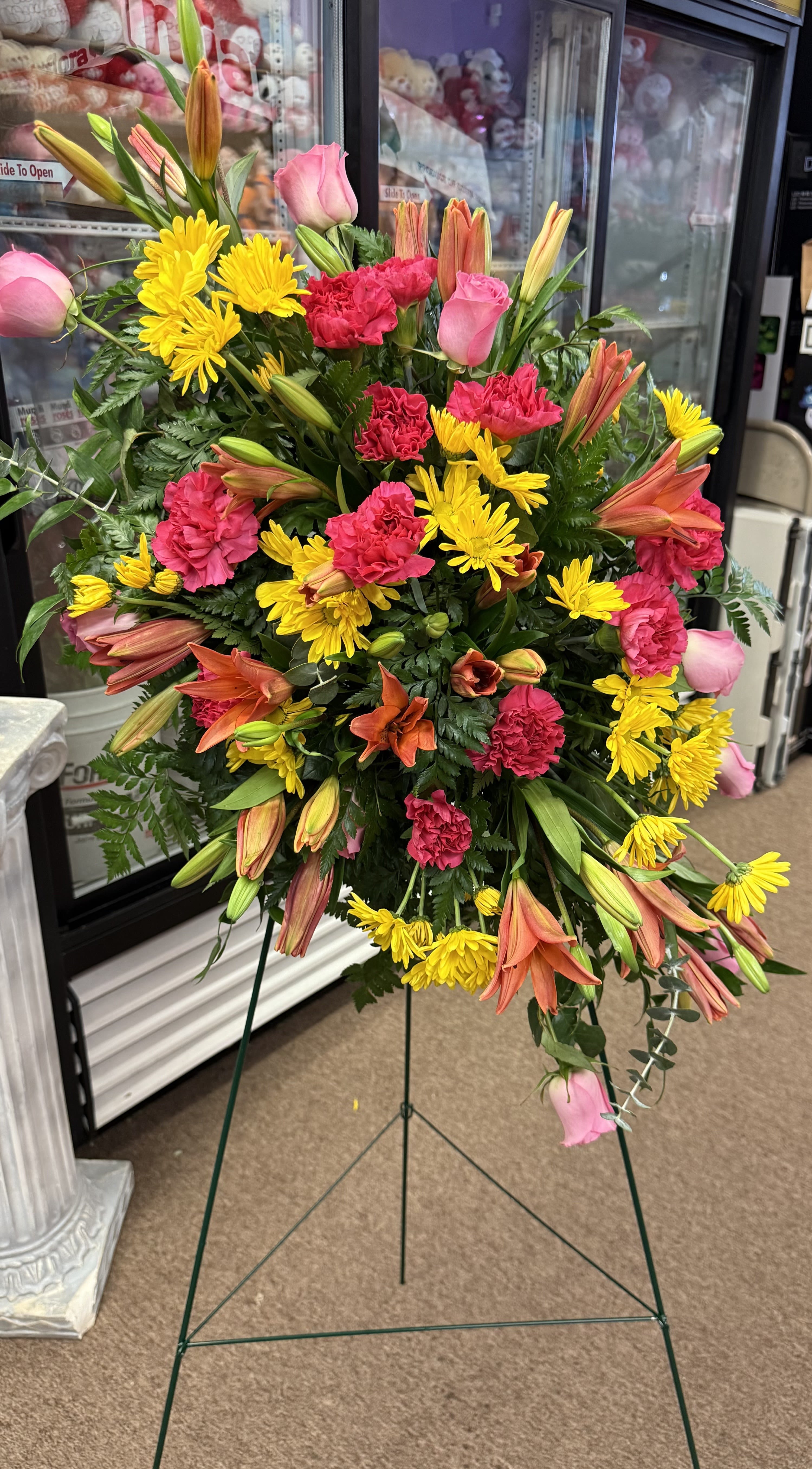 Standing floral spray with pink roses, yellow daisies, and orange lilies