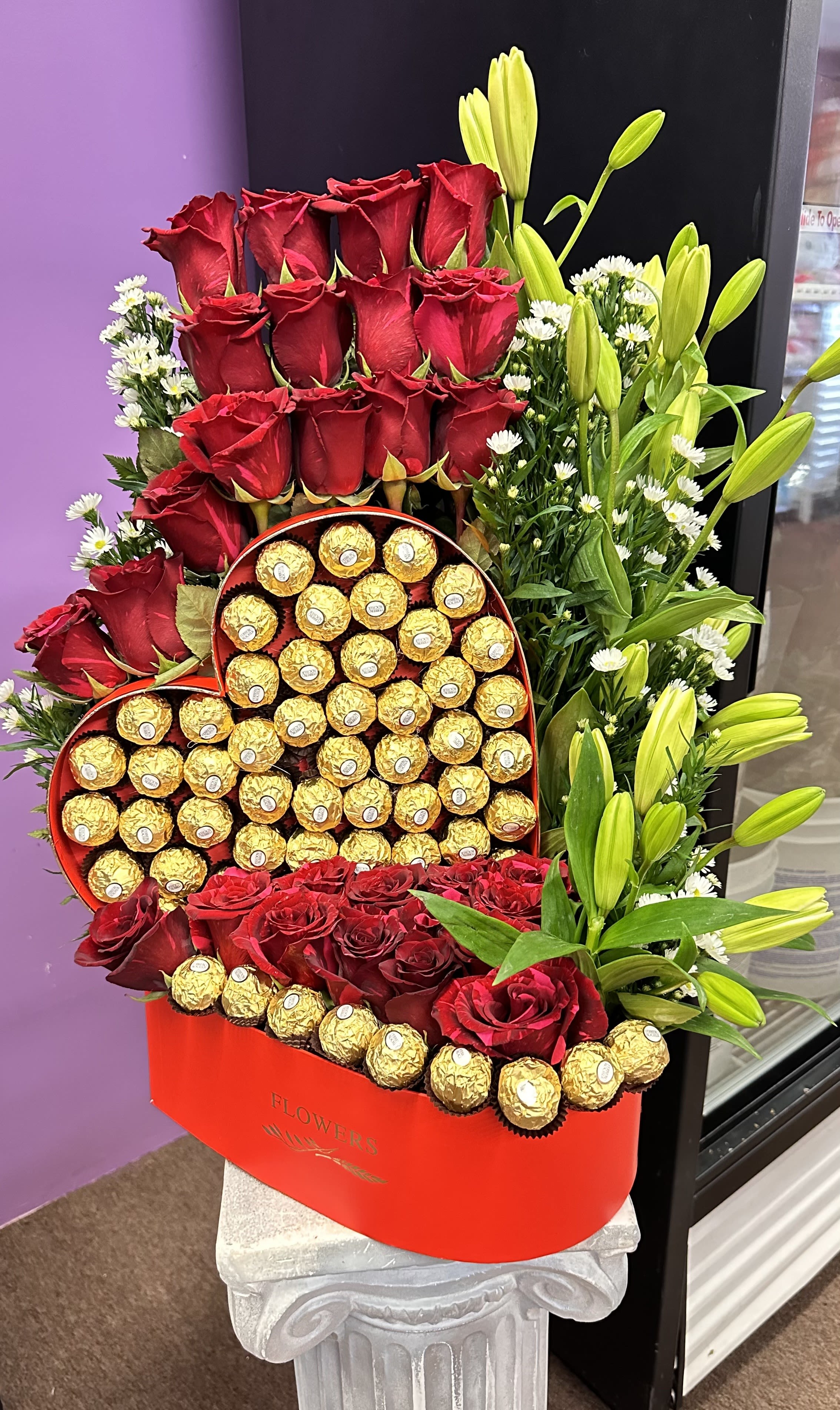 Heart-shaped box of chocolates with red roses and yellow lilies