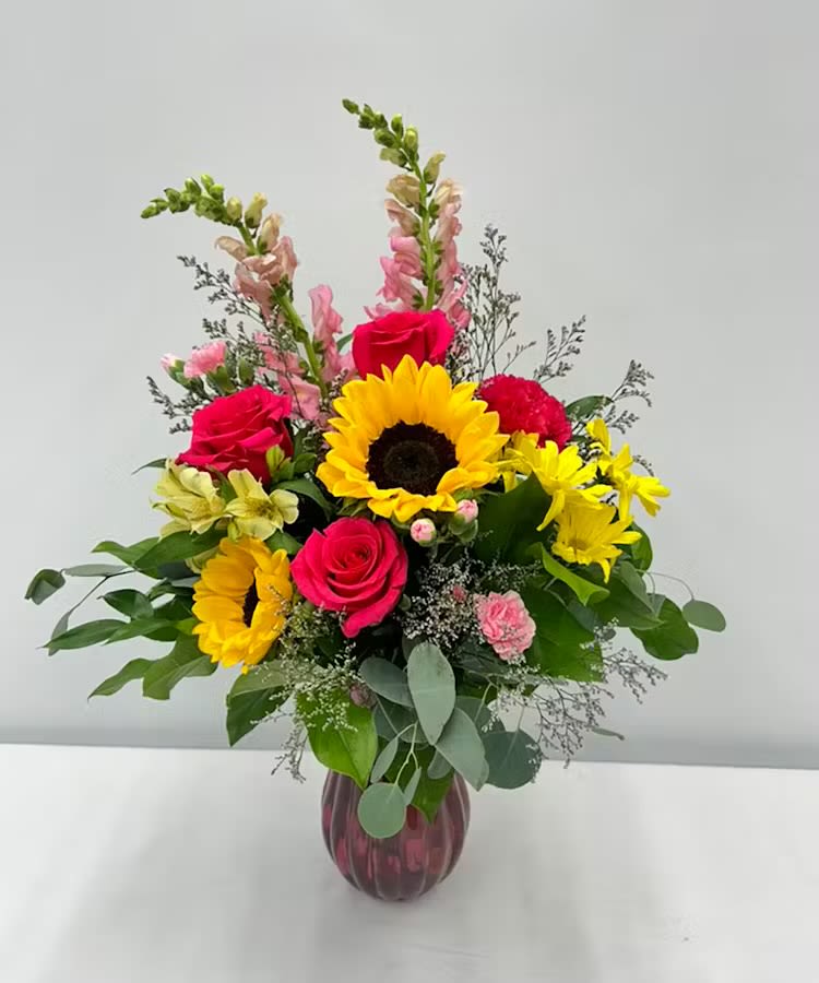 Friday Morning  - “Bring the beauty of nature indoors with this vibrant floral arrangement!  Featuring sunny sunflowers, bold red roses, soft pink accents, and lush greenery, this bouquet is perfect for adding a touch of elegance and warmth to any space. 