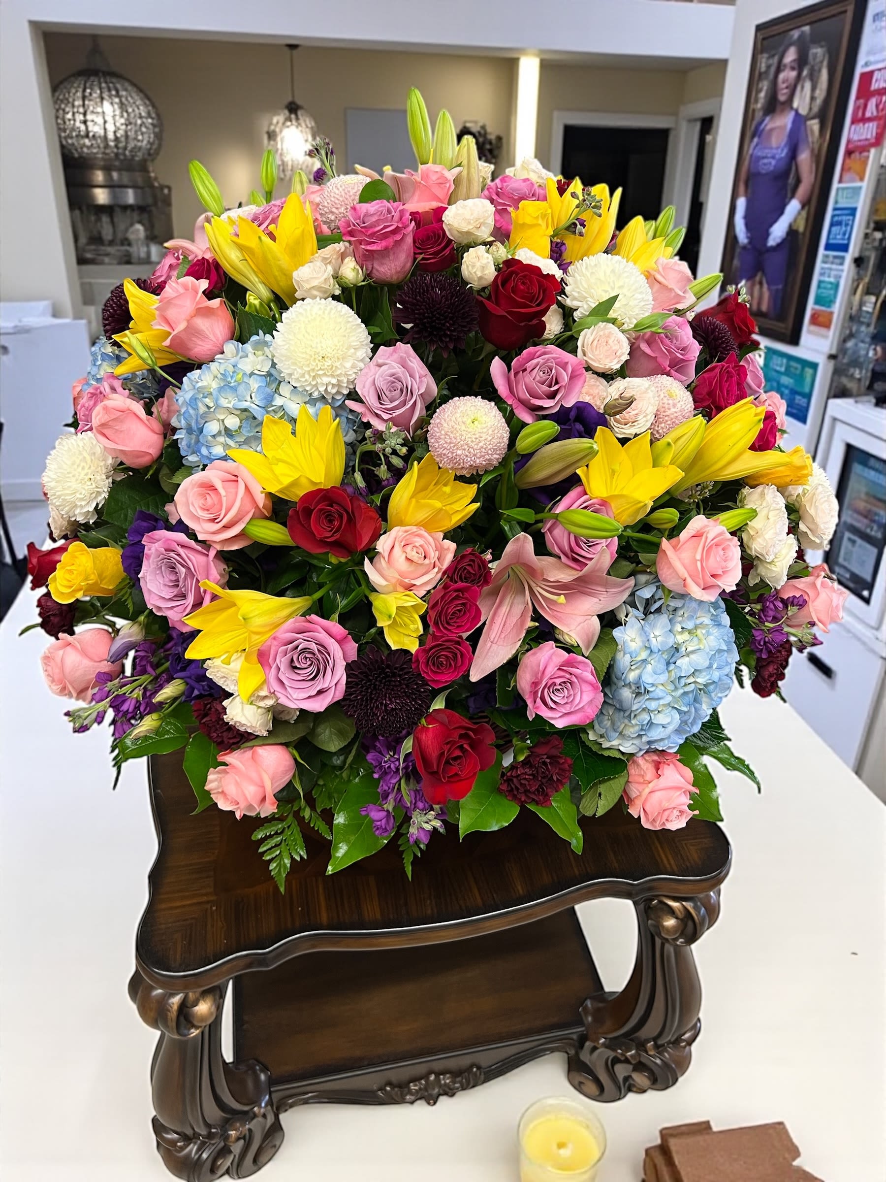 Large mixed bouquet of roses, lilies, and hydrangeas in a dark vase