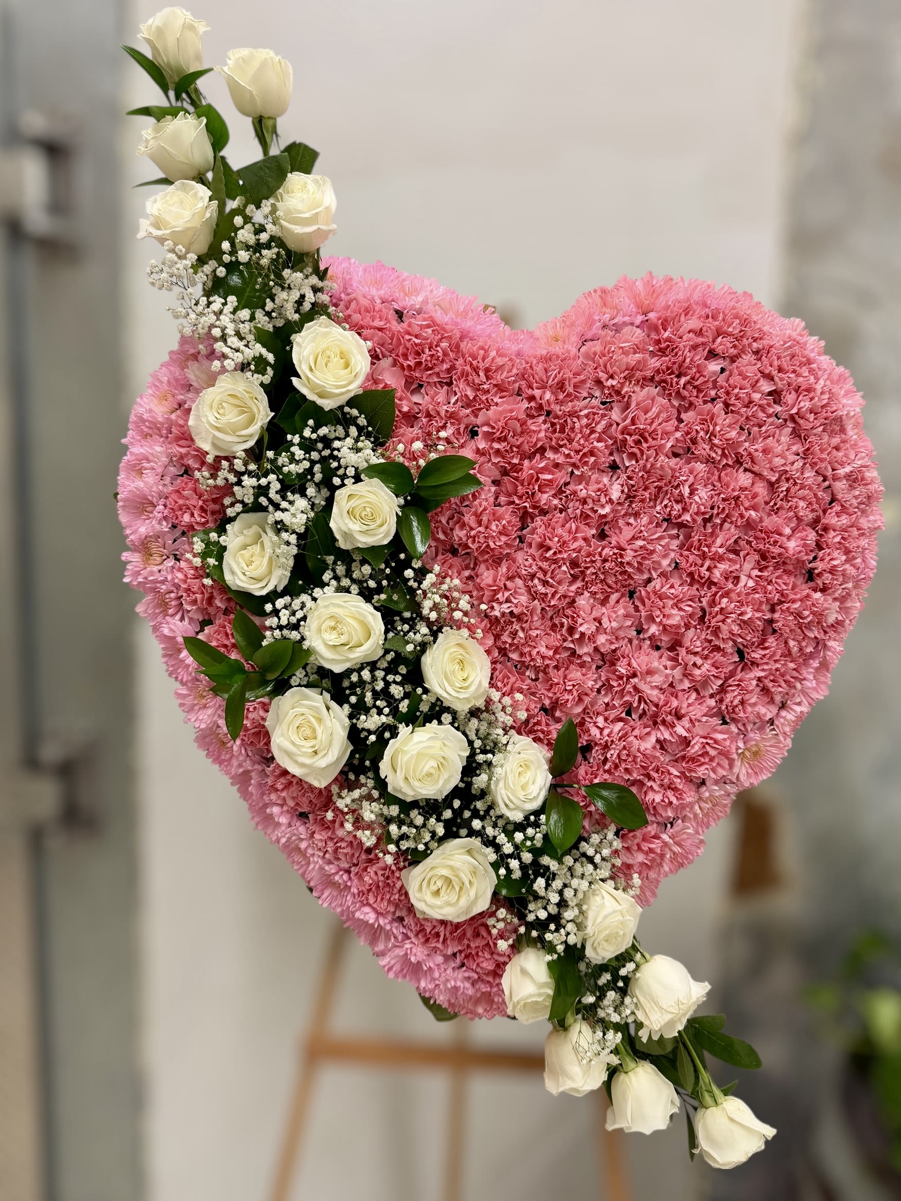 Heart-shaped pink floral arrangement with a diagonal line of white roses