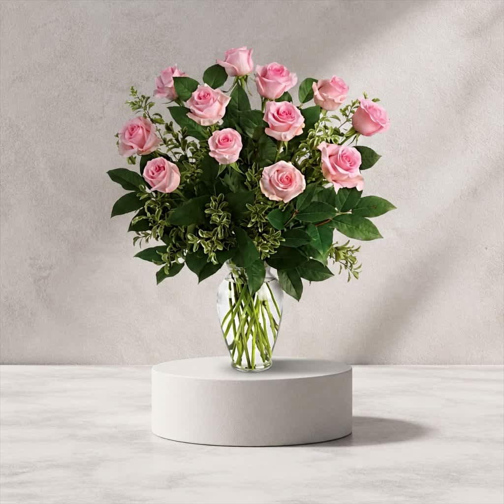 Dozen Pink Roses (DL) - This exquisite flower arrangement showcases the timeless beauty of 12 long stem pink roses, expertly arranged in a clear glass vase. The delicate petals and graceful form of these long stem roses create a stunning display that is both romantic and elegant.
