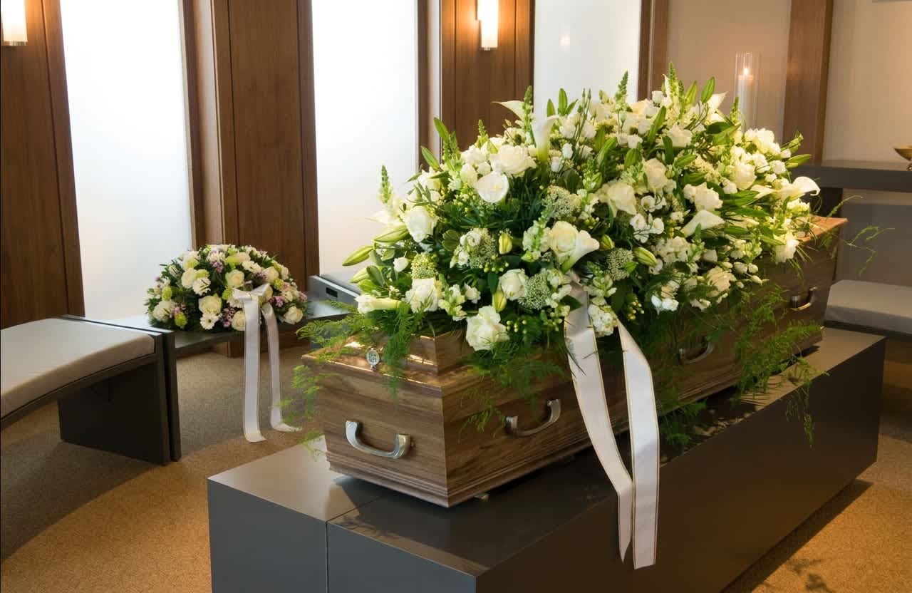 Tranquility casket spray (DL) - Create a stunning farewell with our exquisite casket spray cover, overflowing with an array of pristine white blooms, lush greenery, and delicate filler flowers. This beautiful arrangement, crafted with care and love, pays tribute to a cherished individual and offers a final display of elegance and serenity.