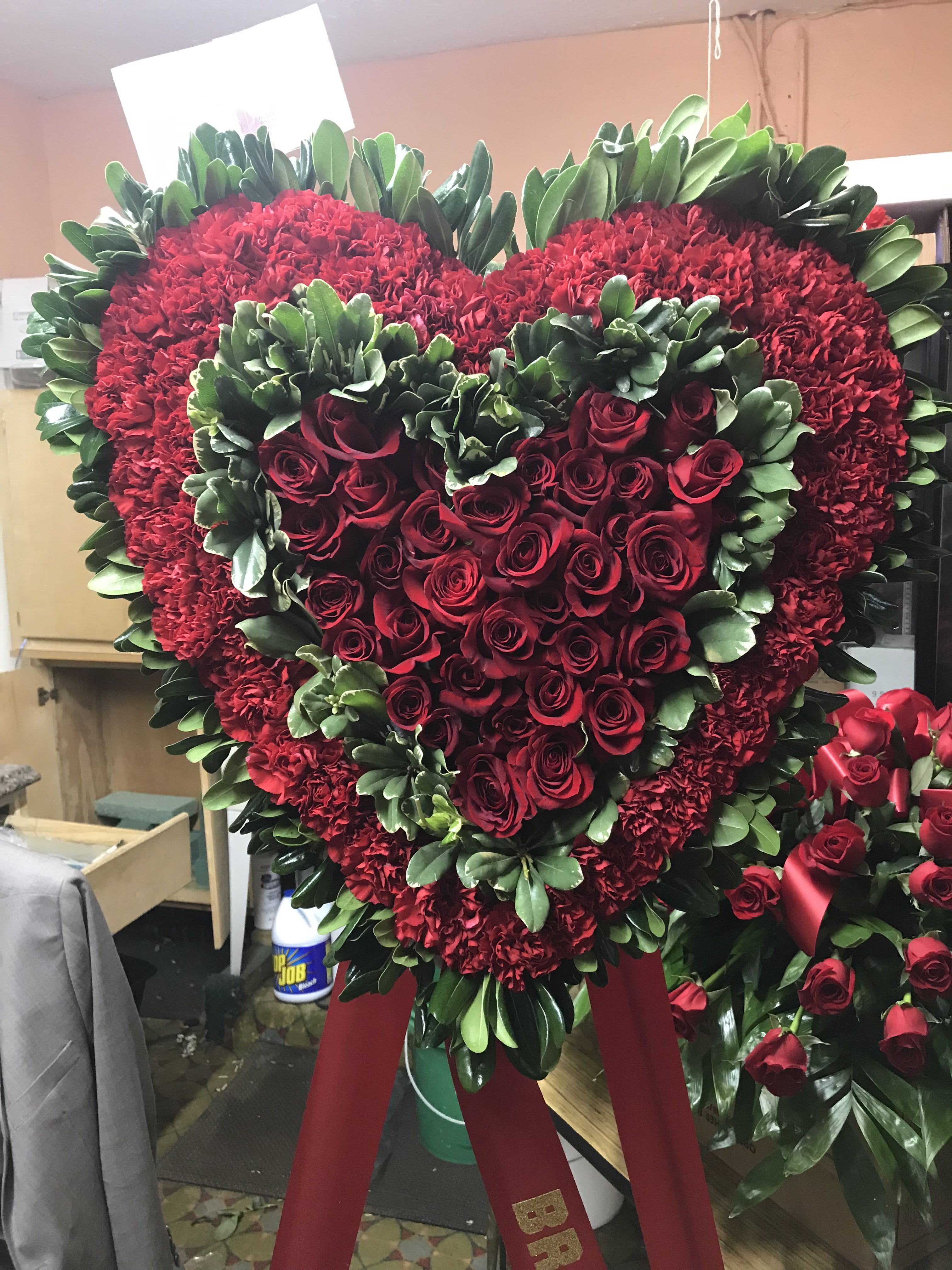 Heart-shaped red rose and carnation wreath on a stand