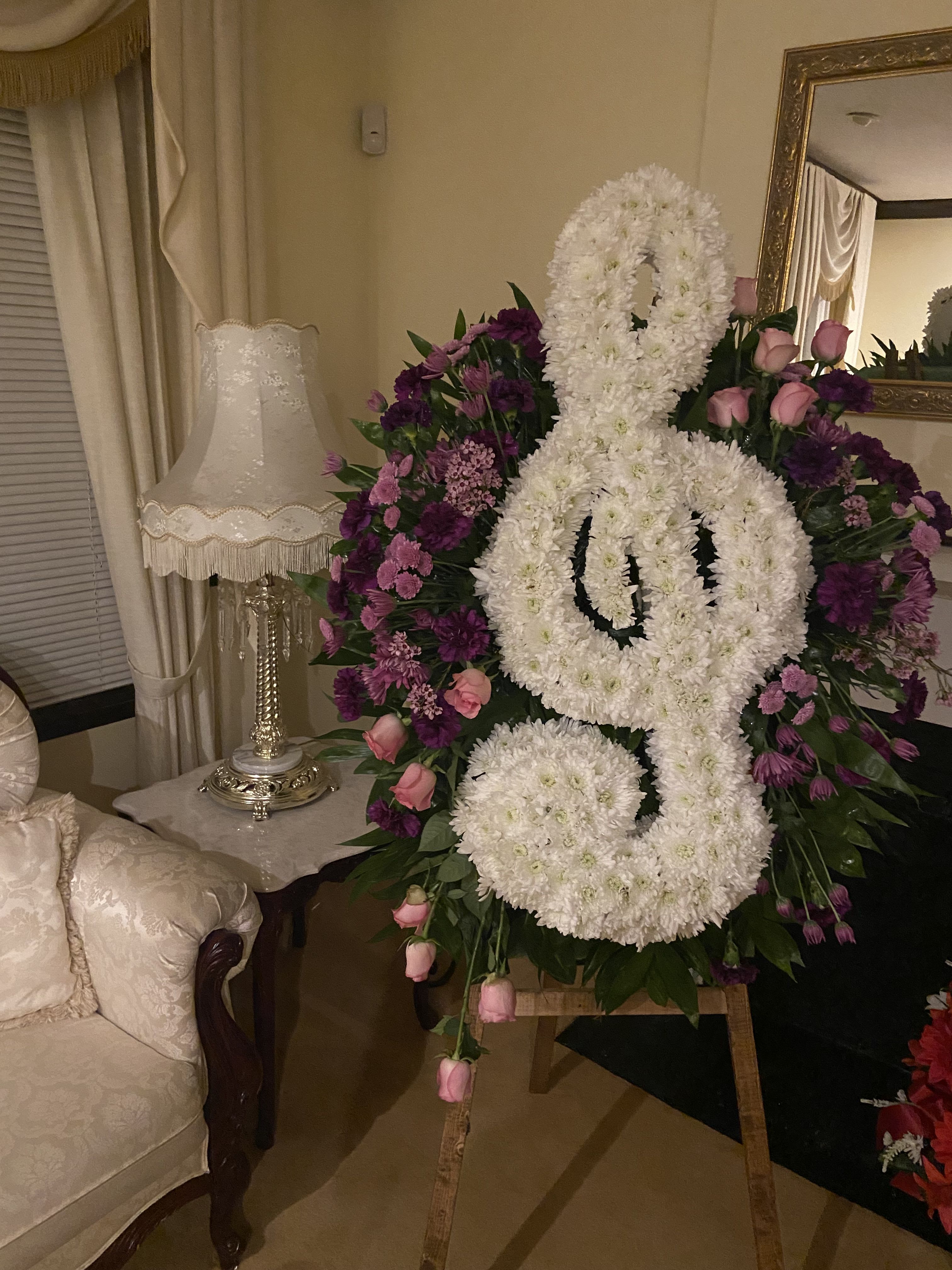 Large white floral funeral spray shaped like a ribbon with pink and purple flowers