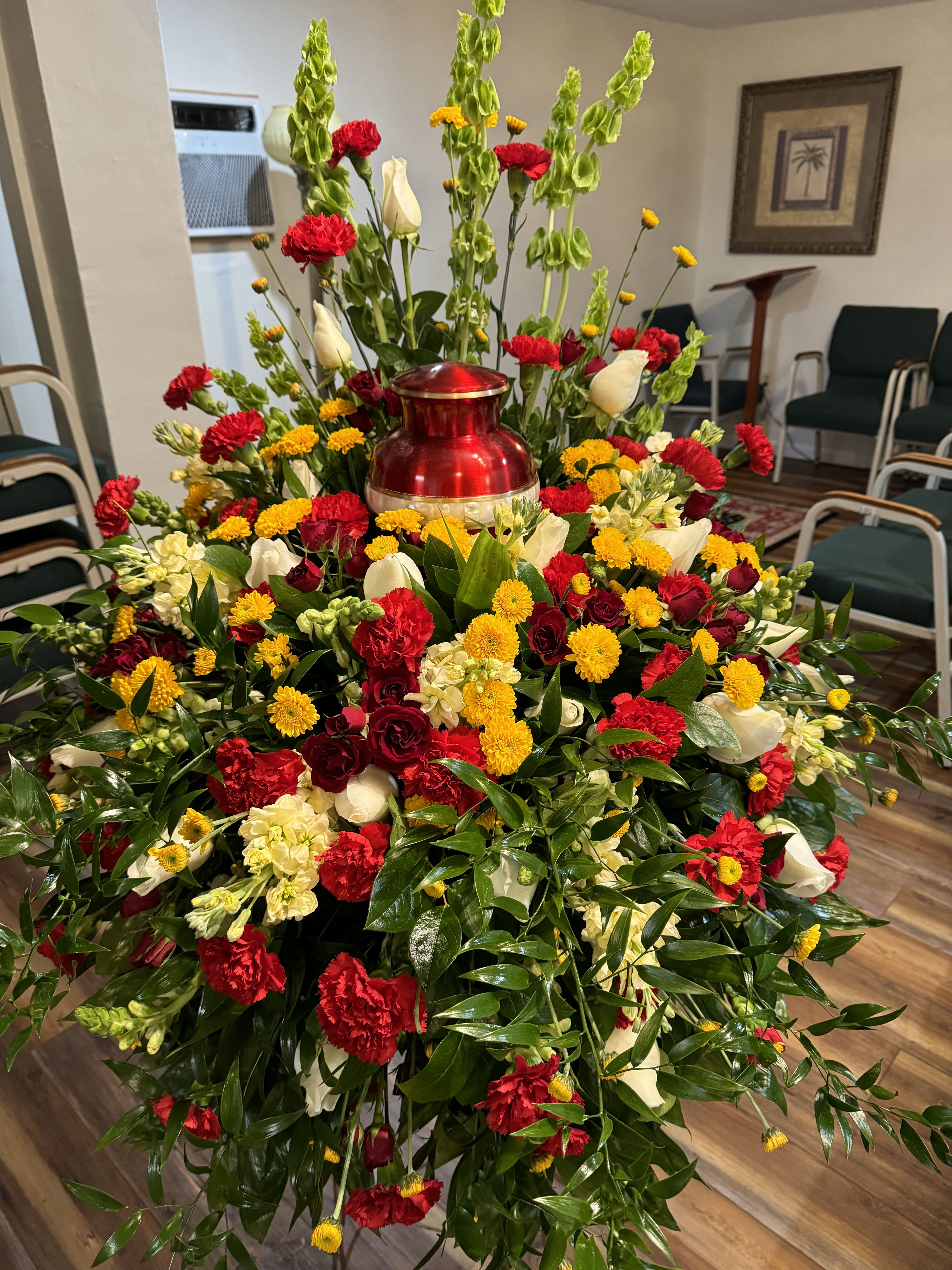 Large red, yellow, and white floral funeral spray with a red urn centerpiece