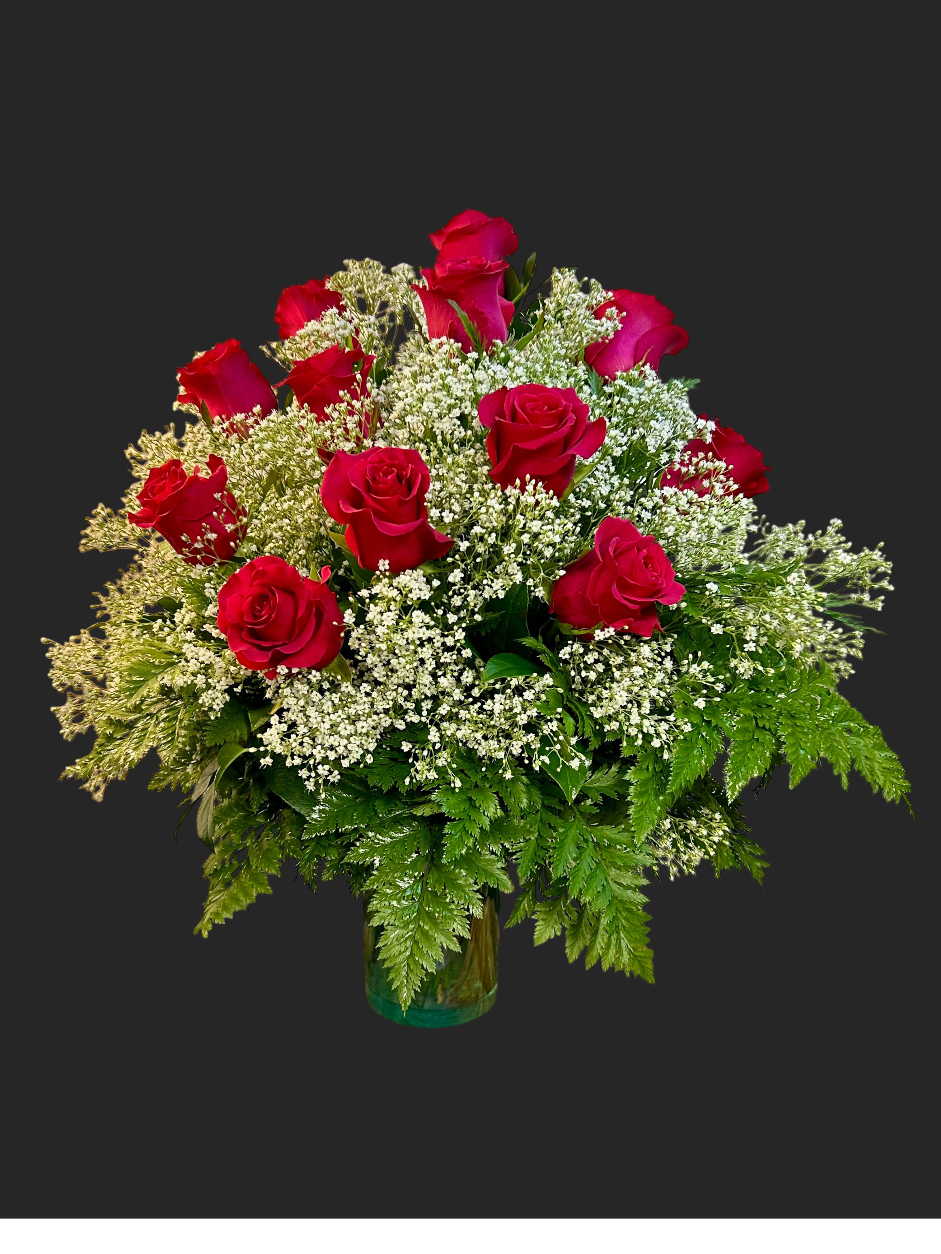 Red roses arranged with white filler flowers in a glass vase
