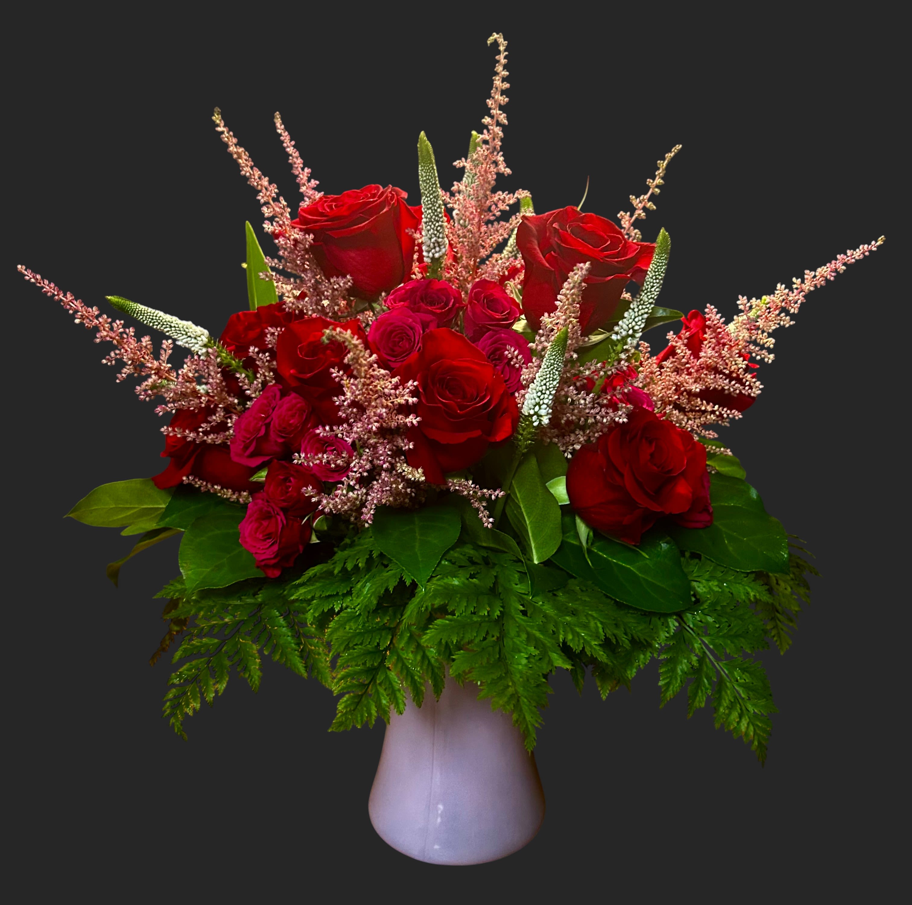 Red roses and pink filler flowers in a white vase