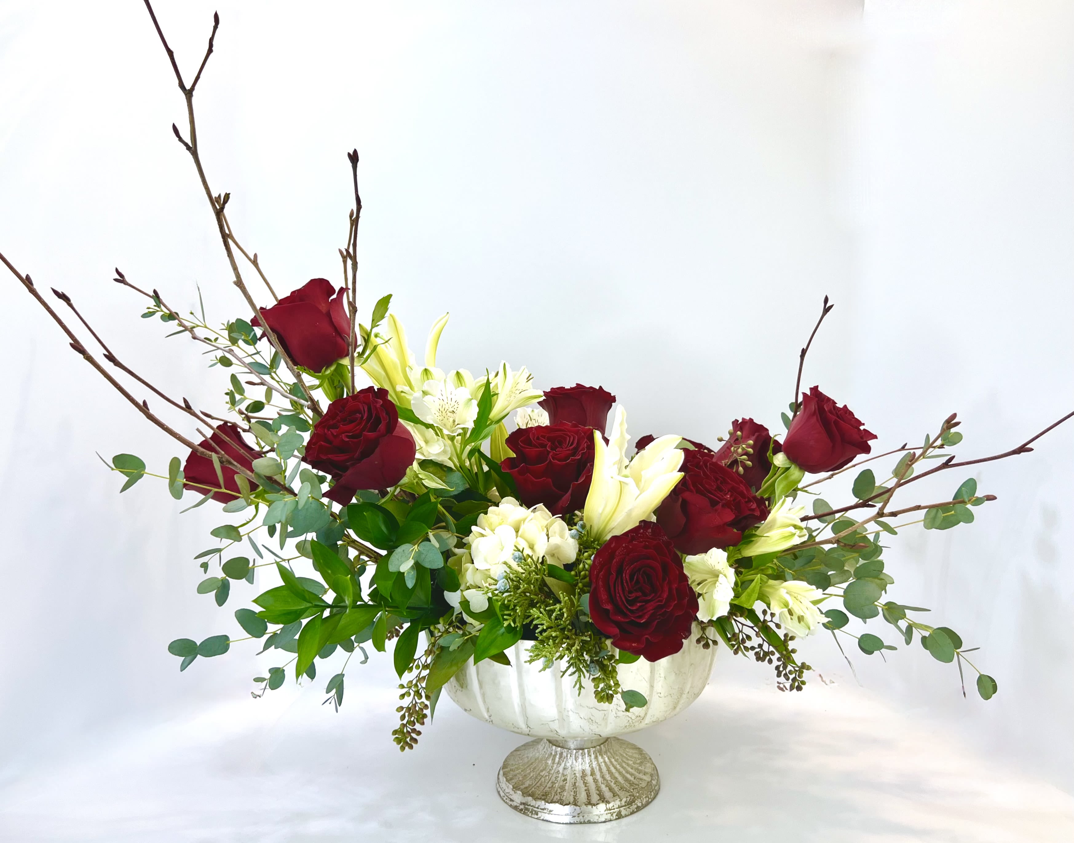 Red roses and white lilies in a white pedestal vase