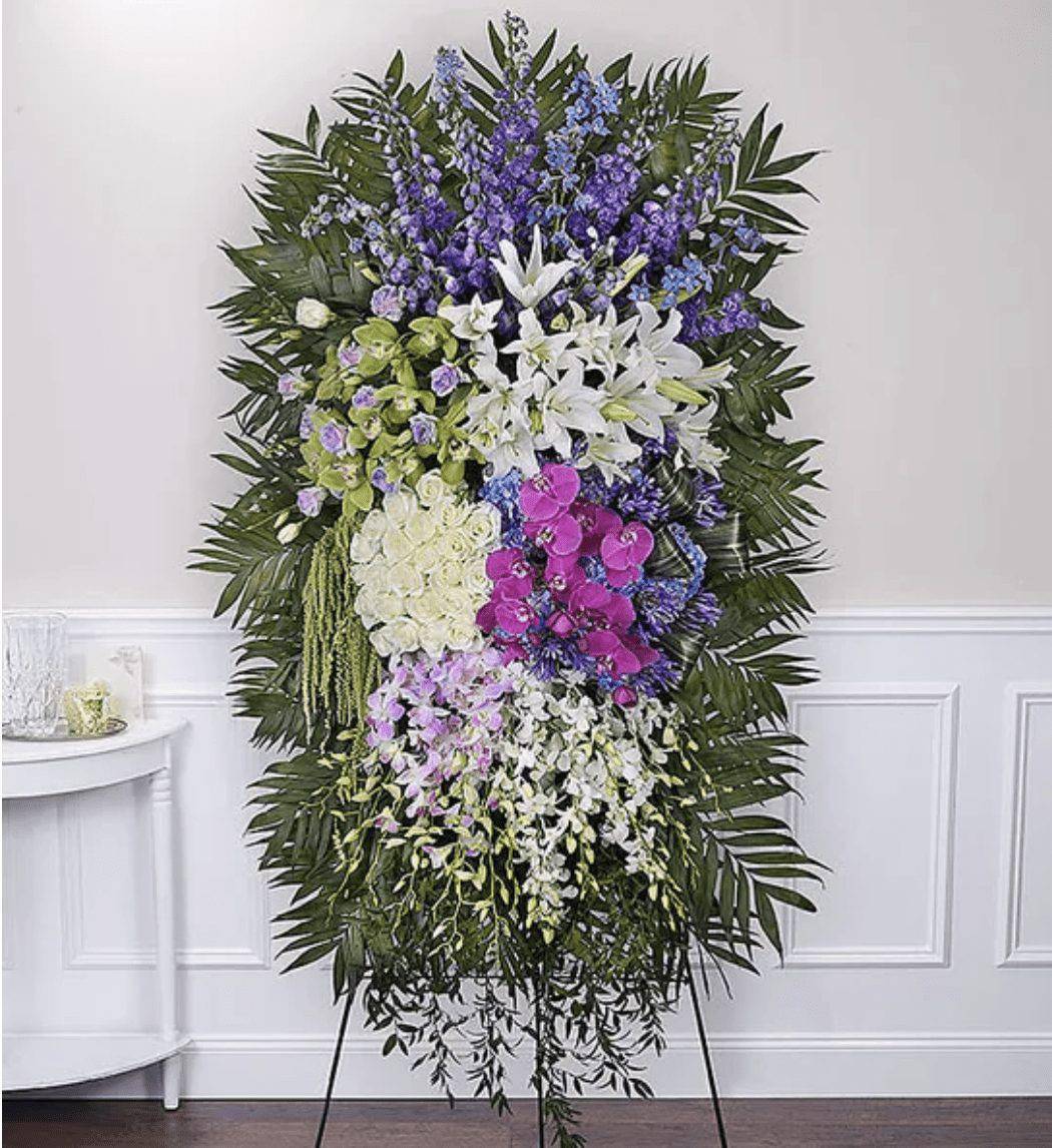 Standing floral spray with white lilies, orchids, and purple blooms