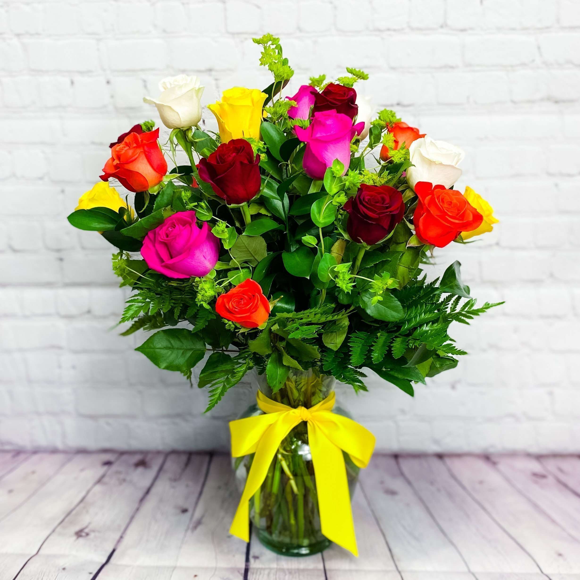 Mixed roses in a glass vase with a yellow ribbon