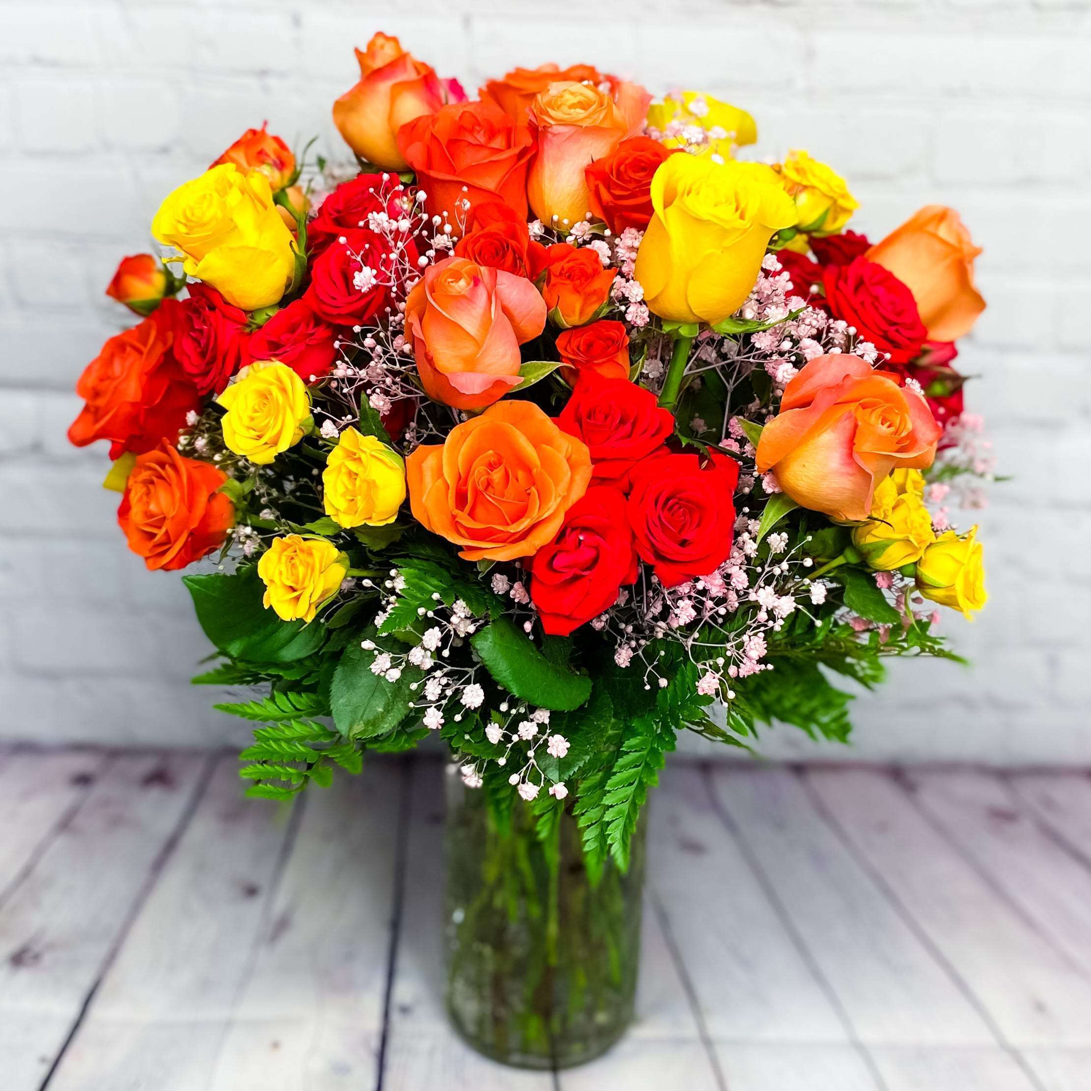 Citrus Exposee - As warm and inviting as a day at the beach or summer sunrise, this invigorating Citrus Exposee arrangement of mouthwatering orange flowers is a gorgeous expression of your love or friendship. Orange and coral roses are gathered with yellow spray rose and fresh greens a keepsake tall glass gathering vase.   --   As warm and inviting as a day at the beach or summer sunrise, this invigorating Citrus Exposee arrangement of mouthwatering orange flowers is a gorgeous expression of your love or friendship. Orange and coral roses are gathered with yellow spray rose and fresh greens a keepsake tall glass gathering vase.