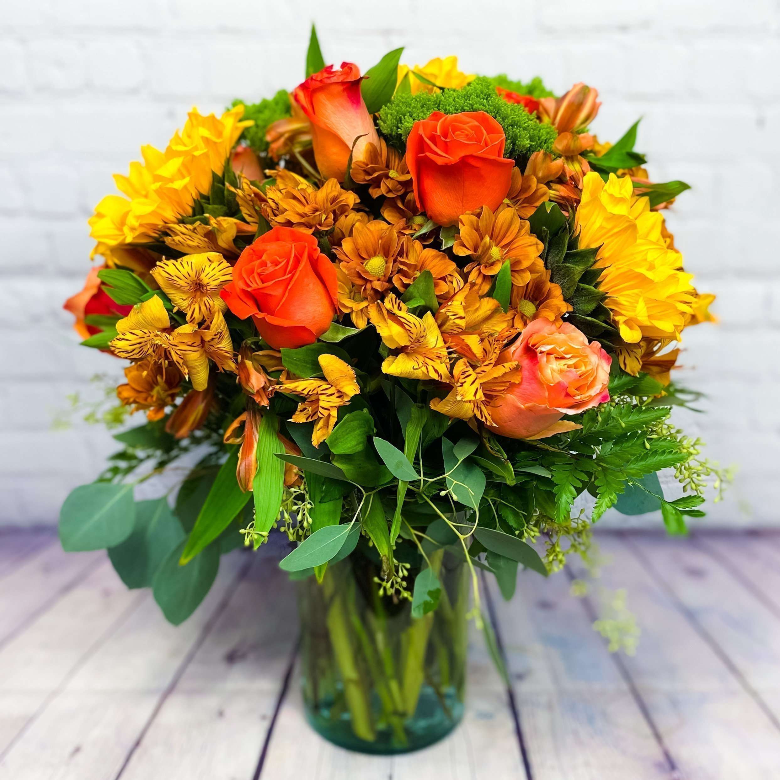 Bouquet of orange roses and yellow flowers in a glass vase