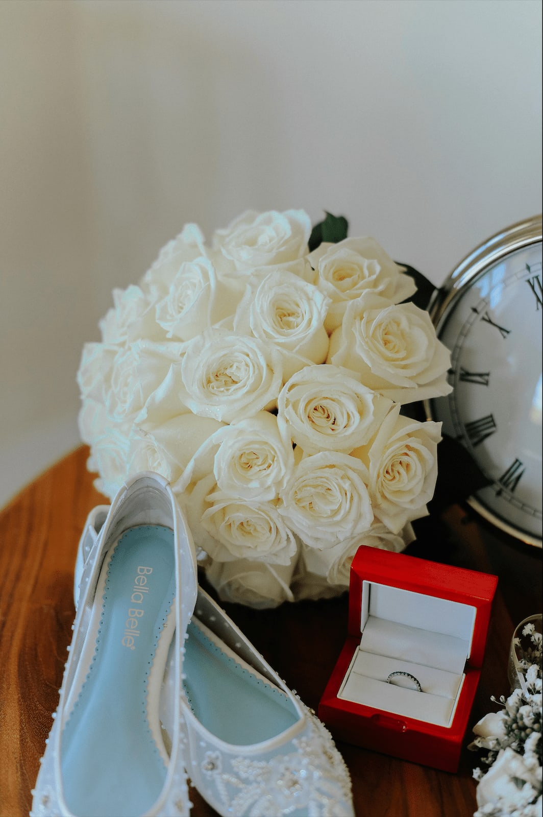 White rose bouquet with bridal shoes, ring box, and clock