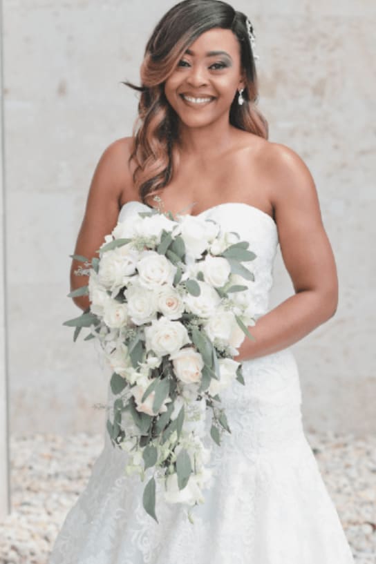 Bride holding a cascading bouquet of white roses and greenery