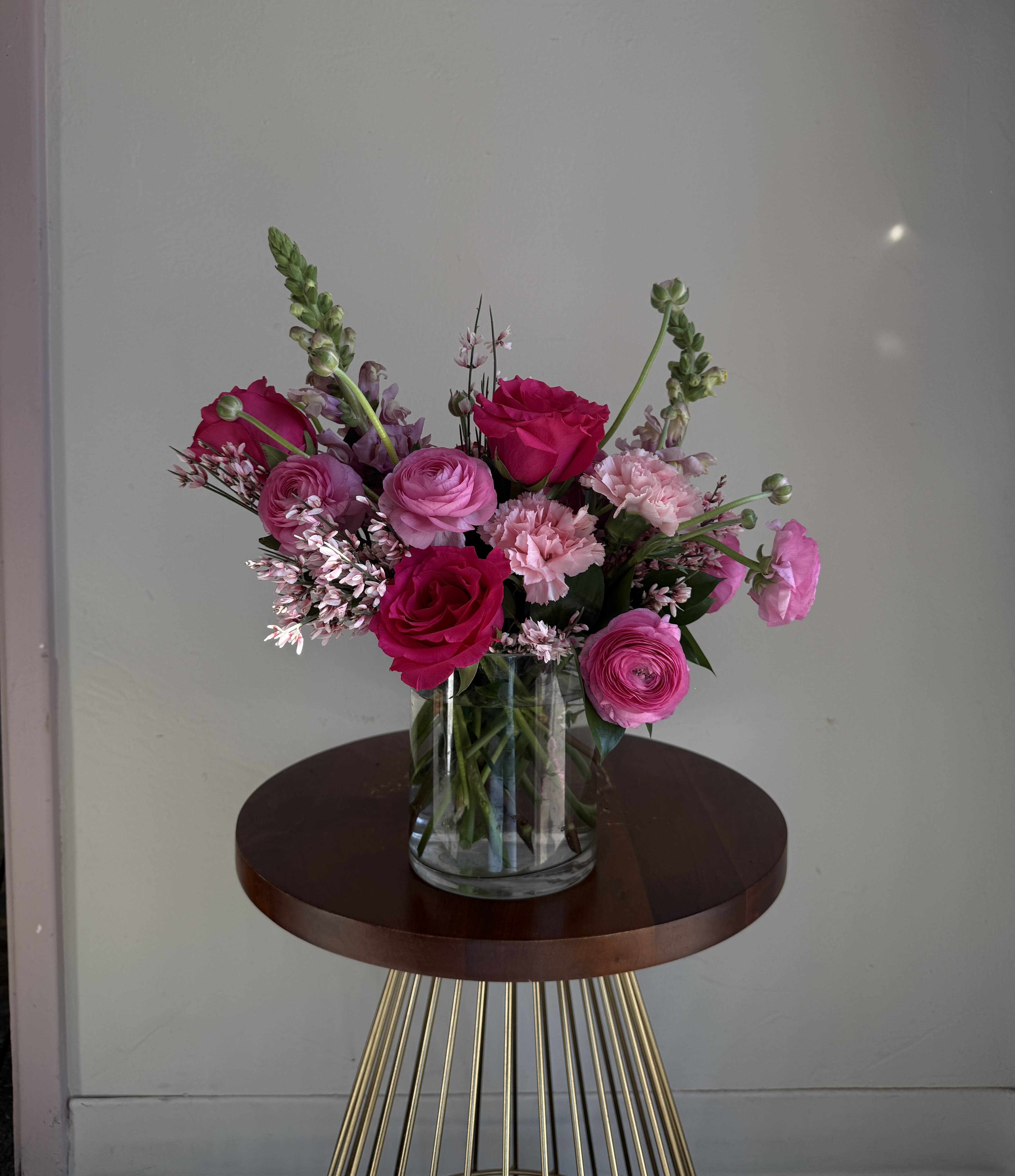 Pink and magenta flowers arranged in a clear glass vase