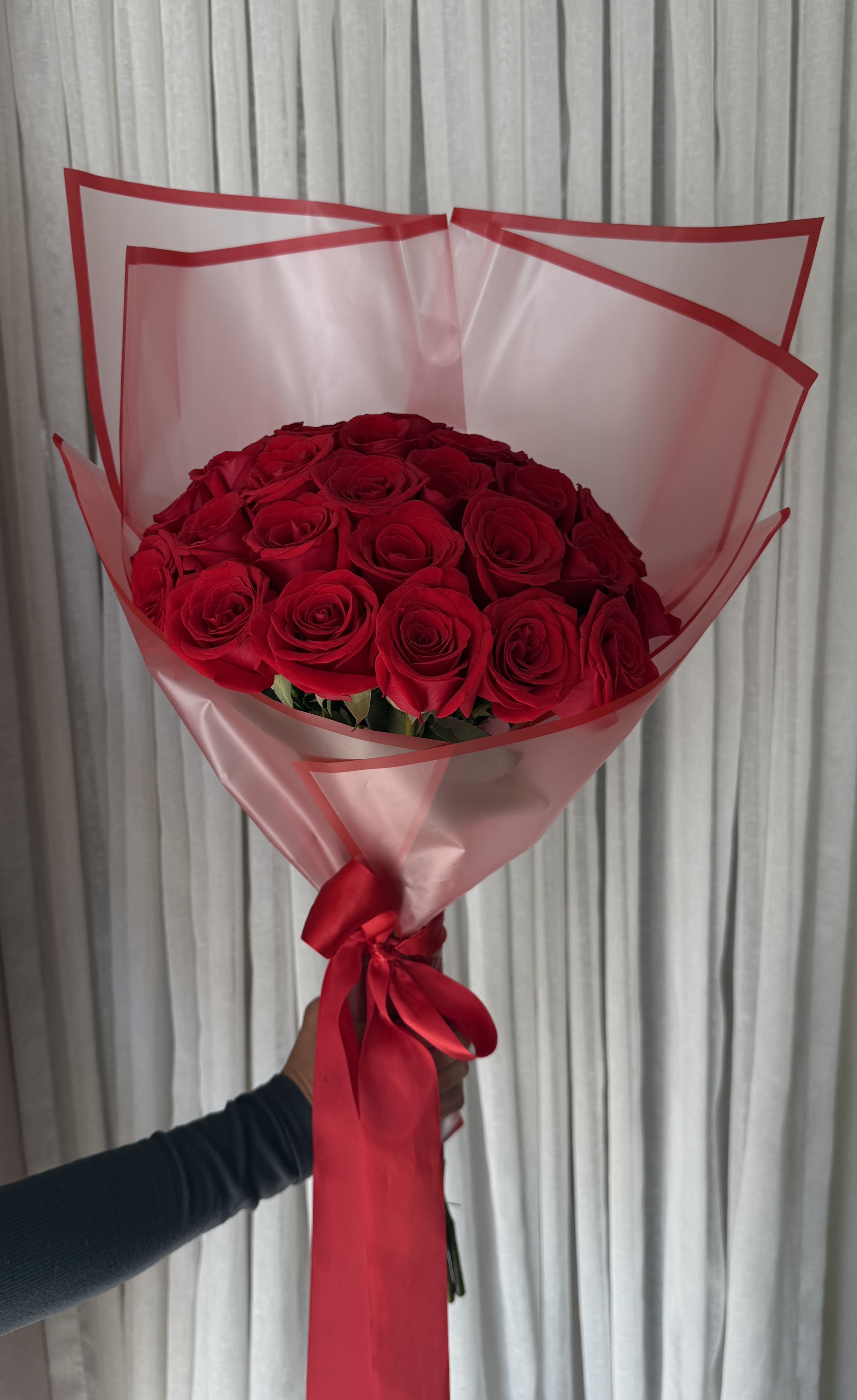 Bouquet of red roses wrapped in pink paper with a red ribbon