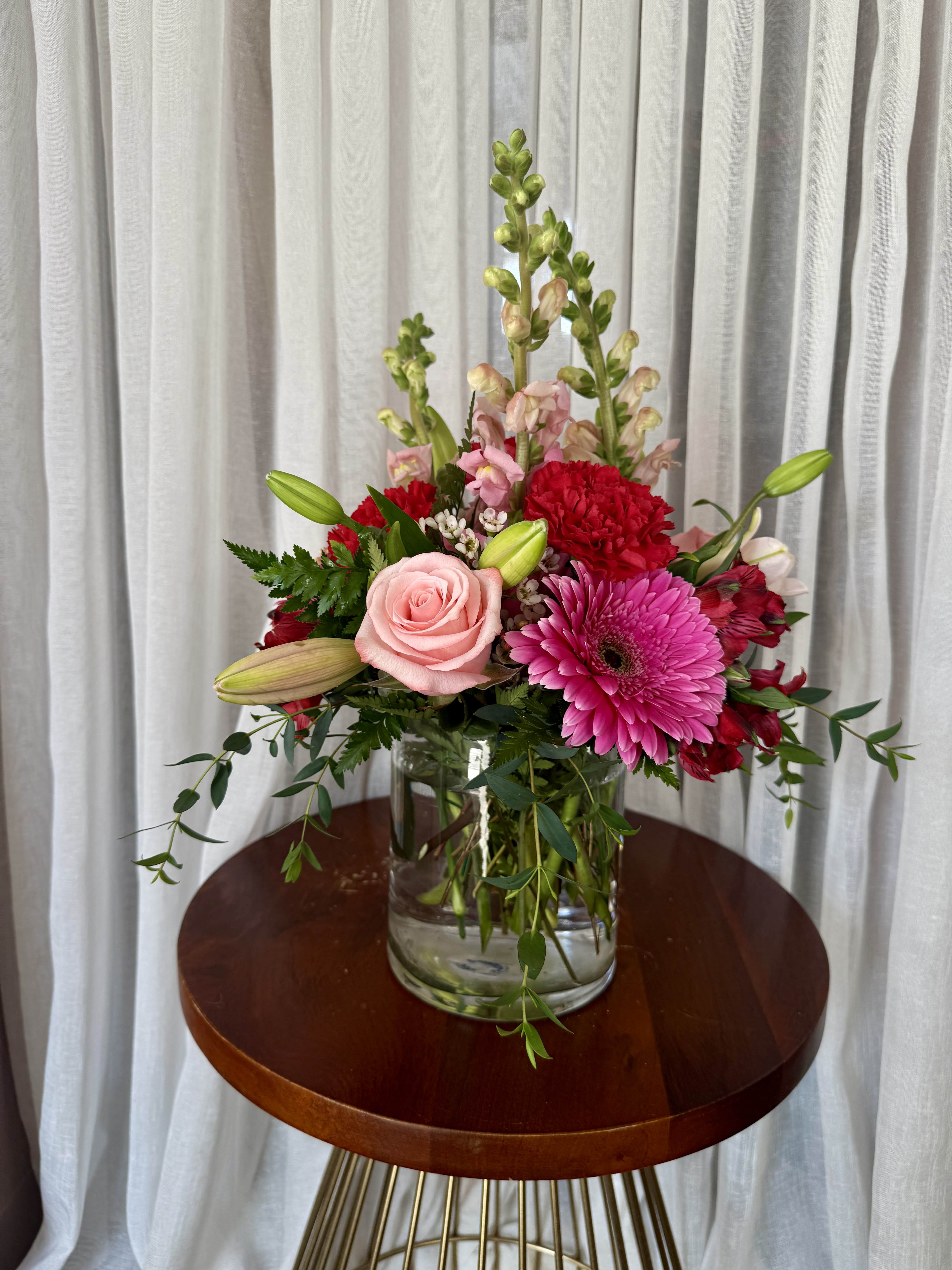Mixed bouquet in a clear glass vase with pink and red blooms