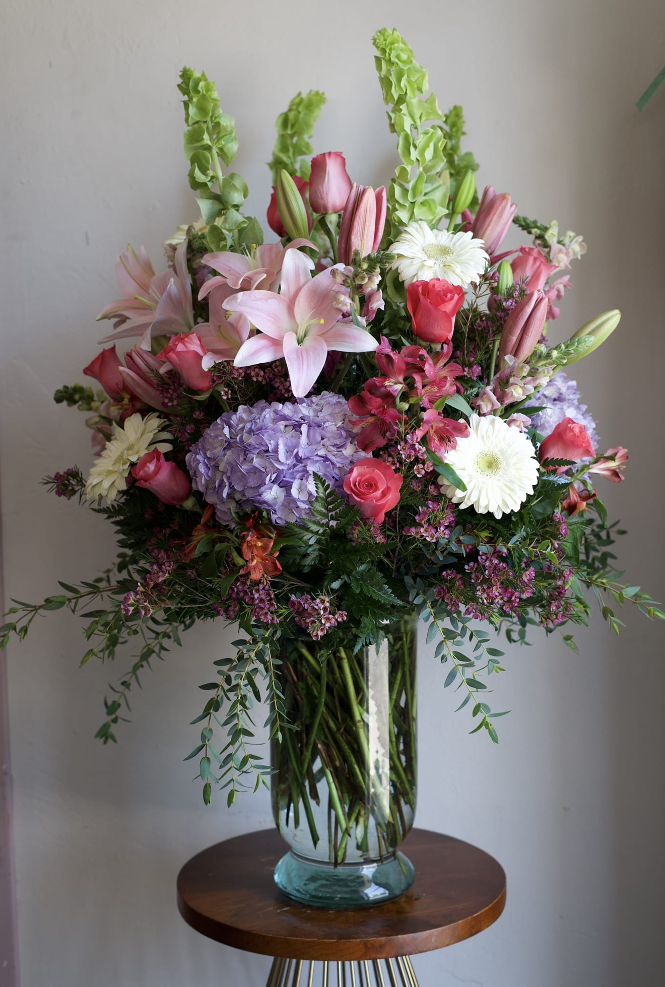 The Grand Blooms  - A lavish, garden-style bouquet that reads as celebration: this flower arrangement makes a bold impression for birthdays, anniversaries, or a heartfelt thank-you. Tall, upright accents and layered blooms create an elegant silhouette, gives the person you're thinking of a romantic yet cheerful gift that commands attention in any room.  Perfect for someone who deserves to feel celebrated, this generous bouquet is sized to be a focal point and to last through several days of enjoyment.