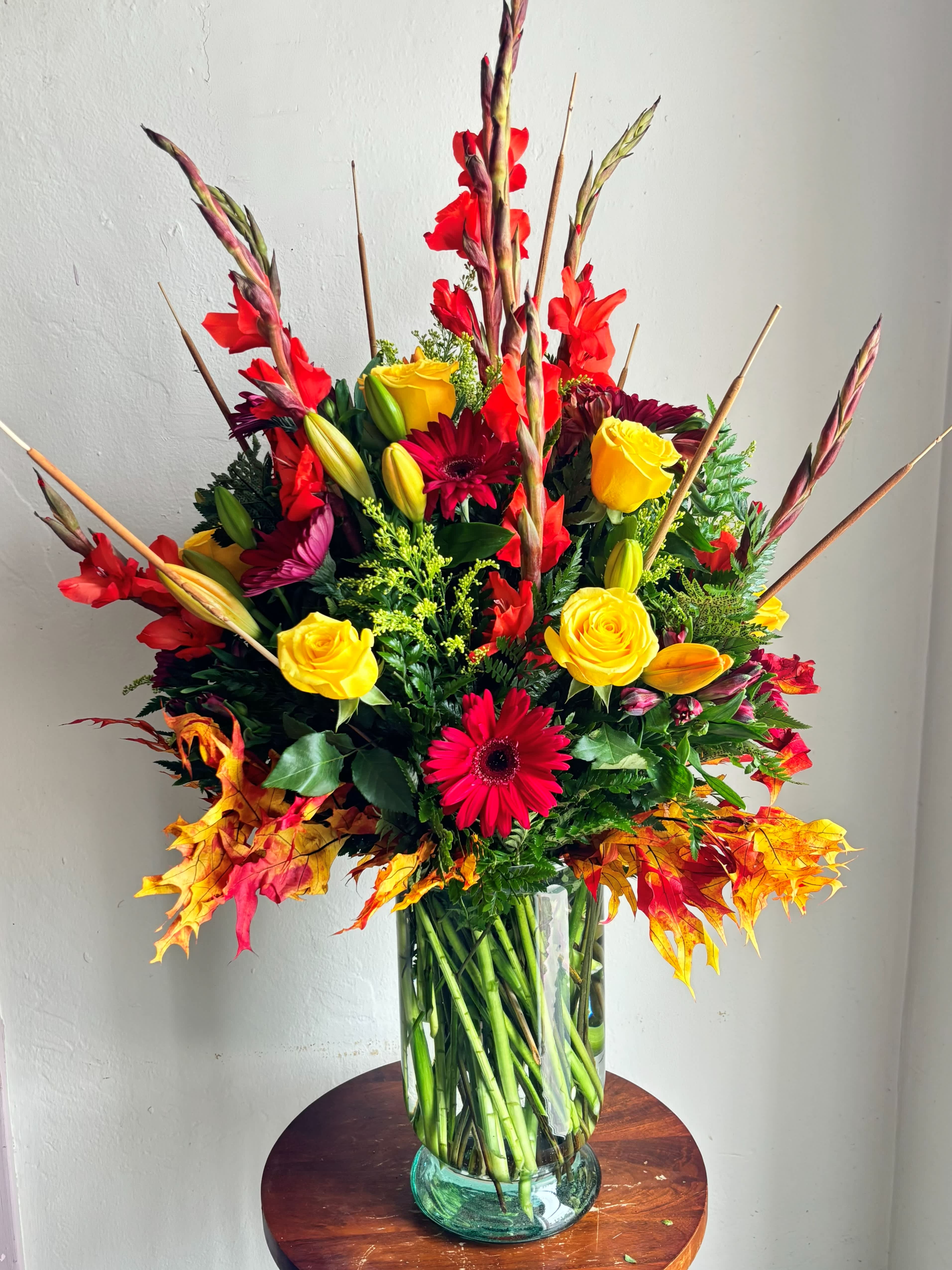 Tall mixed bouquet in a glass vase with red, yellow, and orange flowers