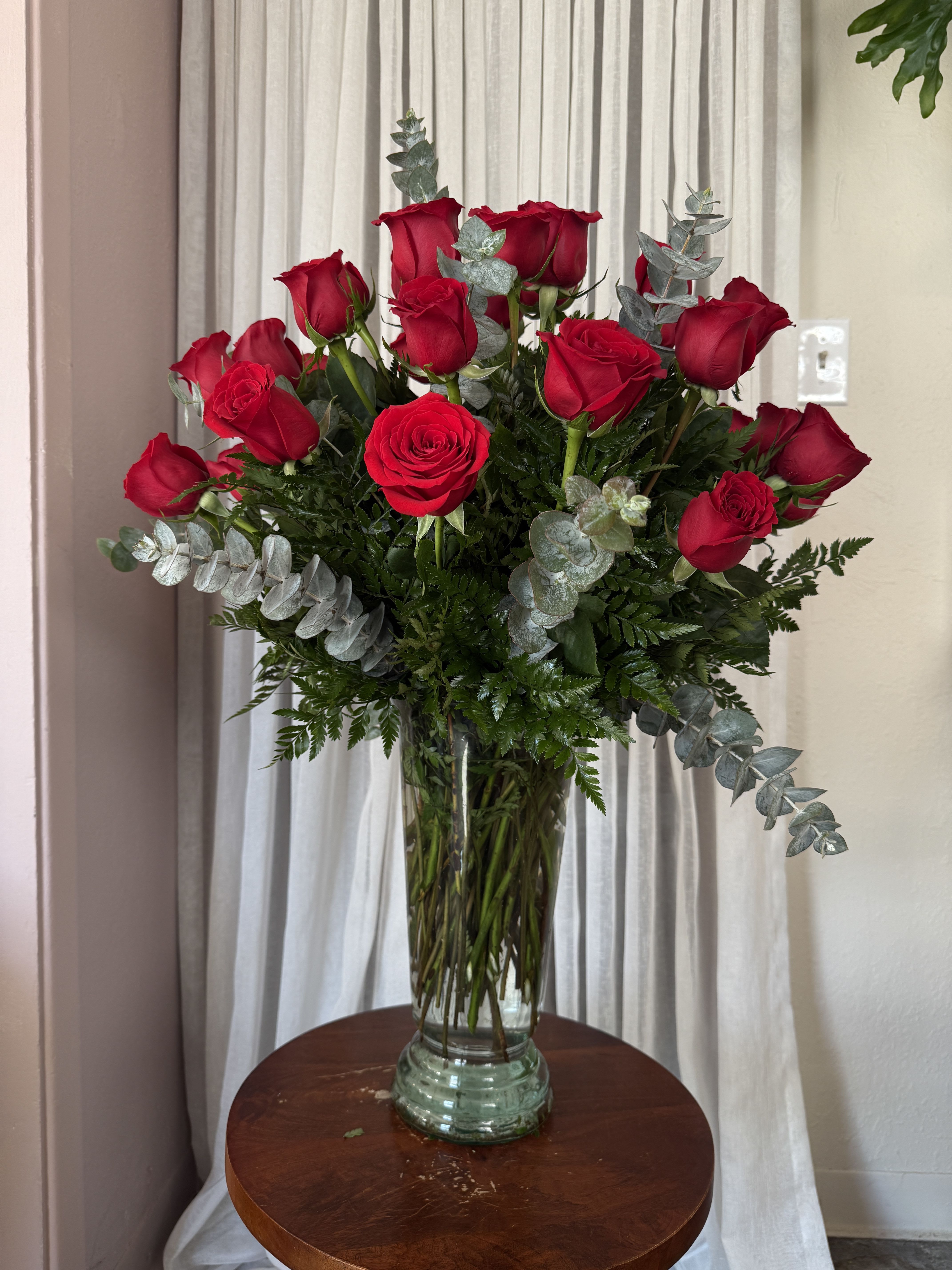 Red roses in a clear glass vase with silver eucalyptus