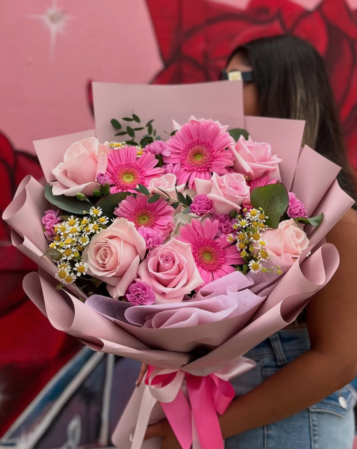 Pink bouquet of roses and gerbera daisies wrapped in pastel paper