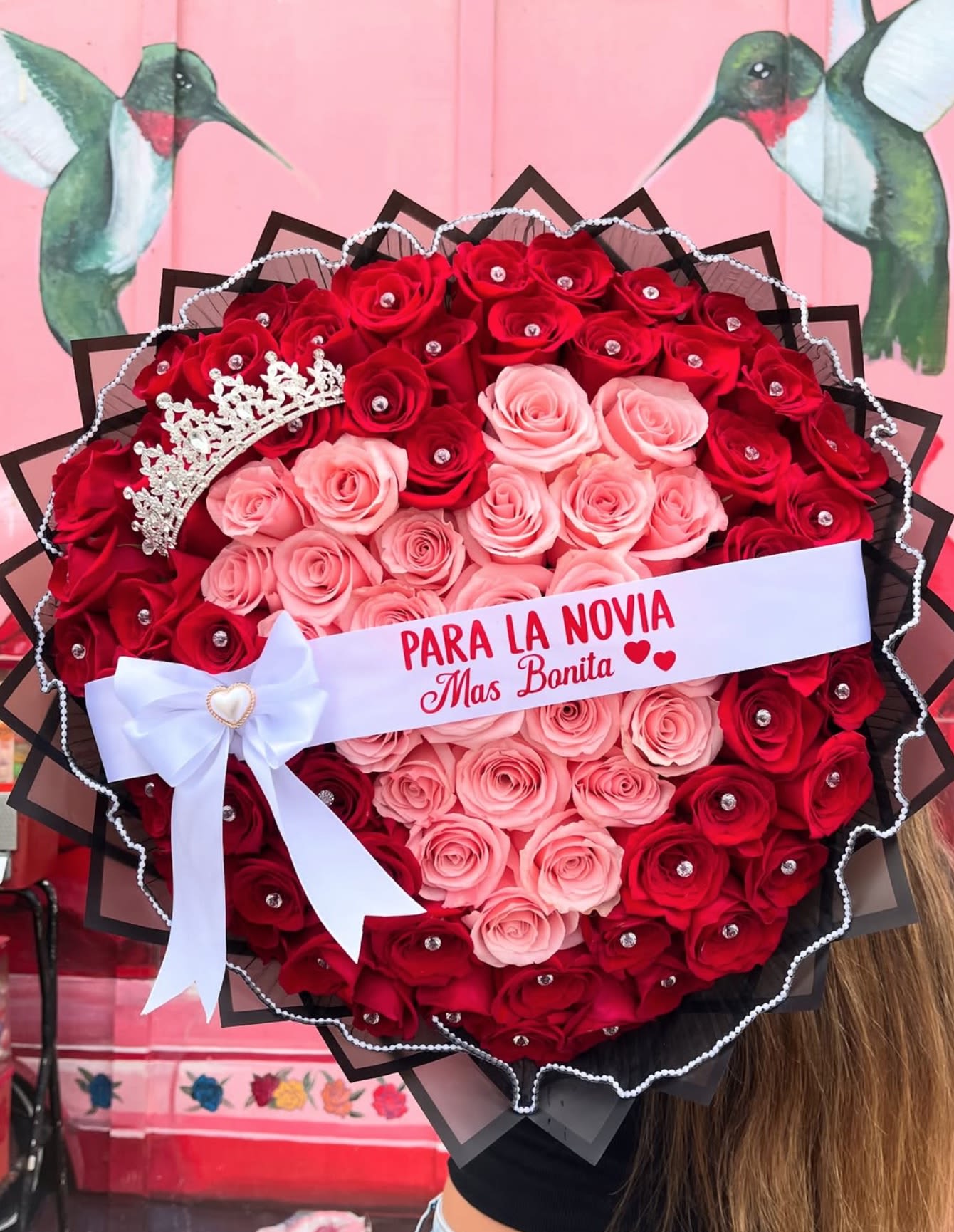 Heart-shaped bouquet of red and pink roses with a tiara and ribbon