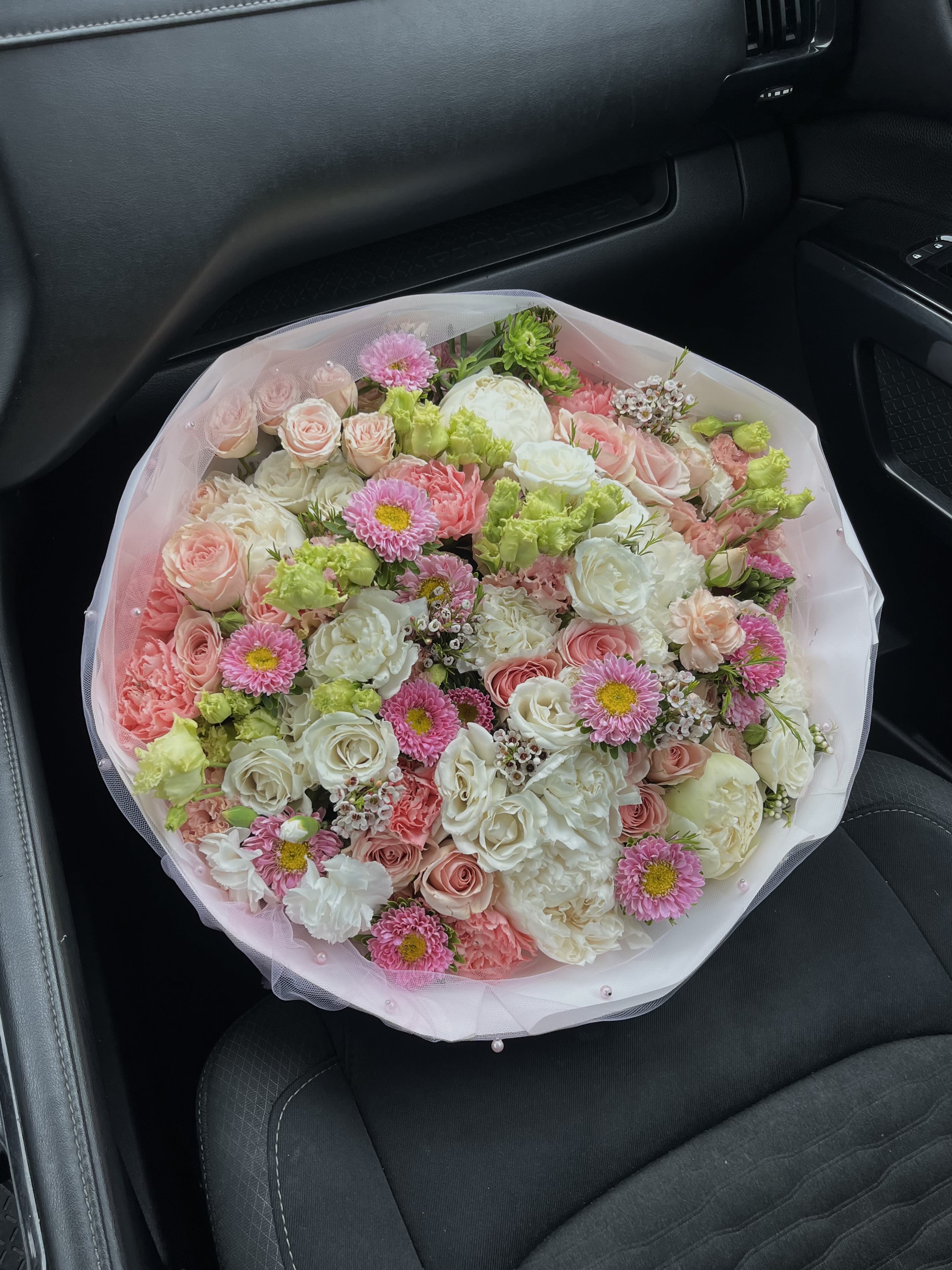 Large bouquet of pink, white, and green flowers wrapped in pale pink mesh