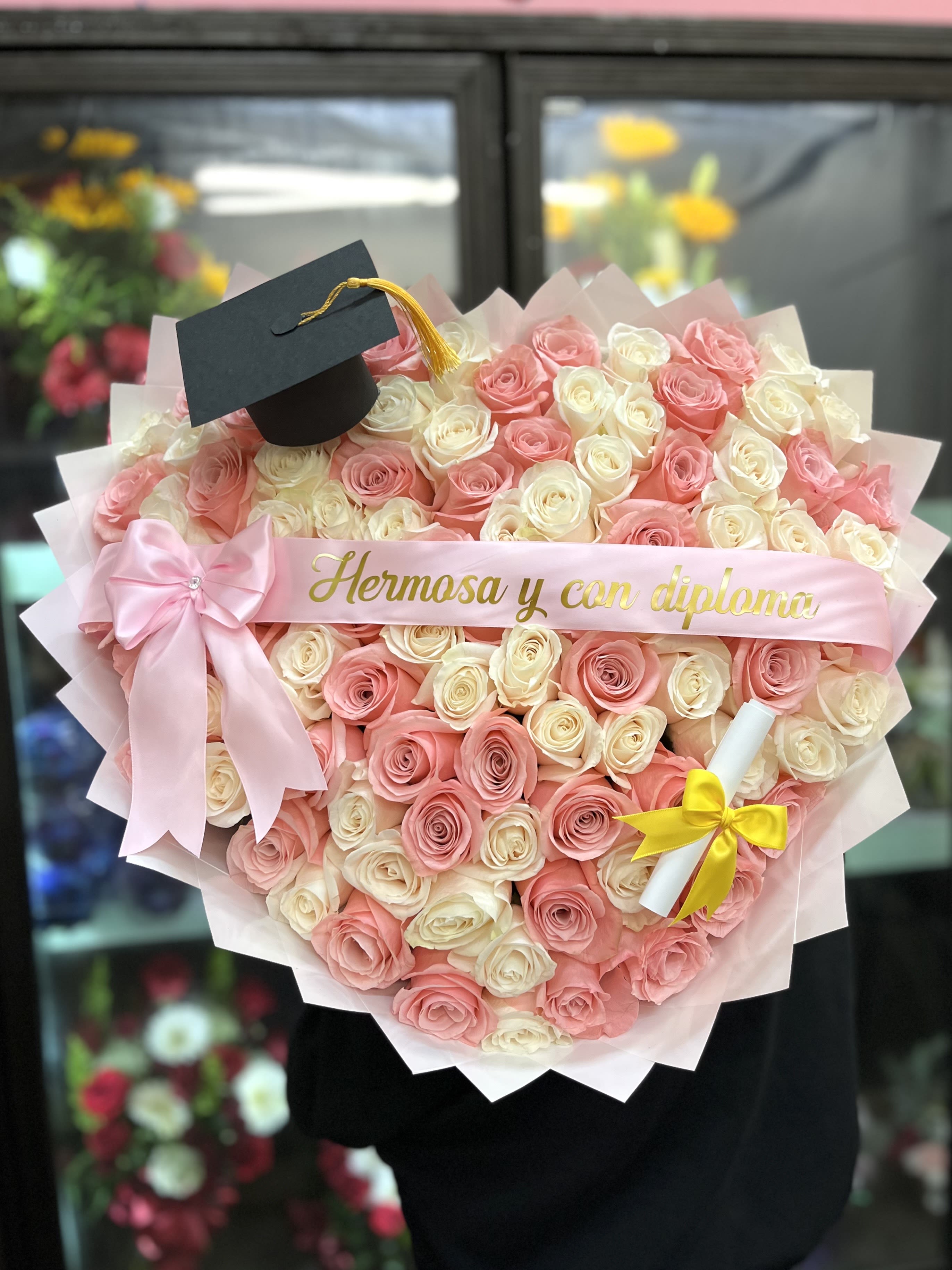 Heart-shaped bouquet of pink and white roses with a graduation cap topper